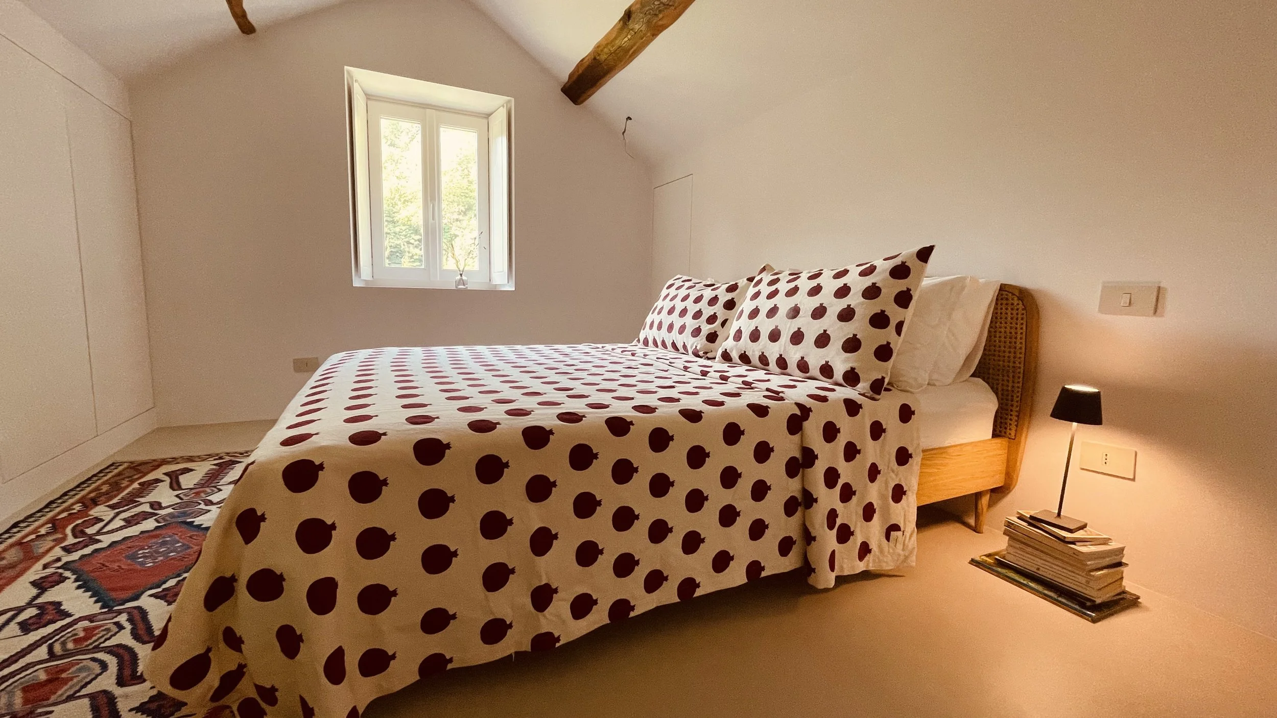 Cielo Suite bedroom at Villa Oberti with exposed timber beams and patterned bed linen, in a charming private villa near Mondovì in Piedmont