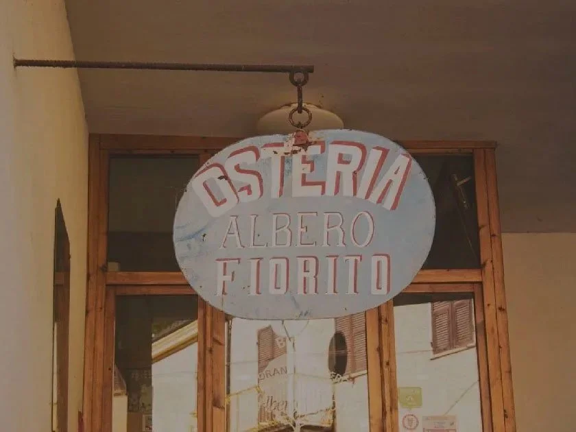 Cartello della trattoria 'Osteria Albero Fiorito' appeso all'ingresso