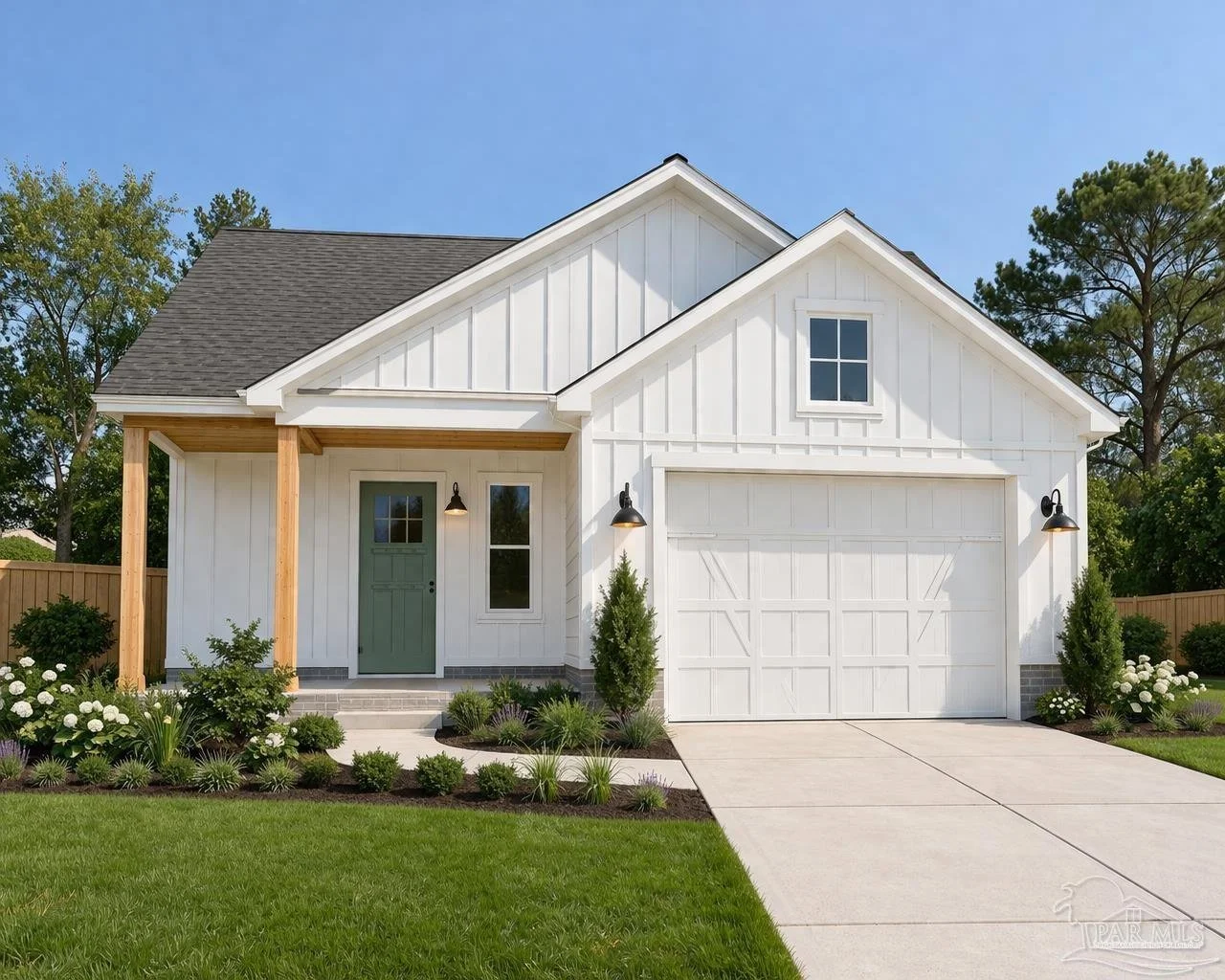 A modern white house with a gabled roof, front porch with wooden posts, green front door, black outdoor wall lamps, attached garage, and landscaped front yard with bushes and flowers, under a blue sky.