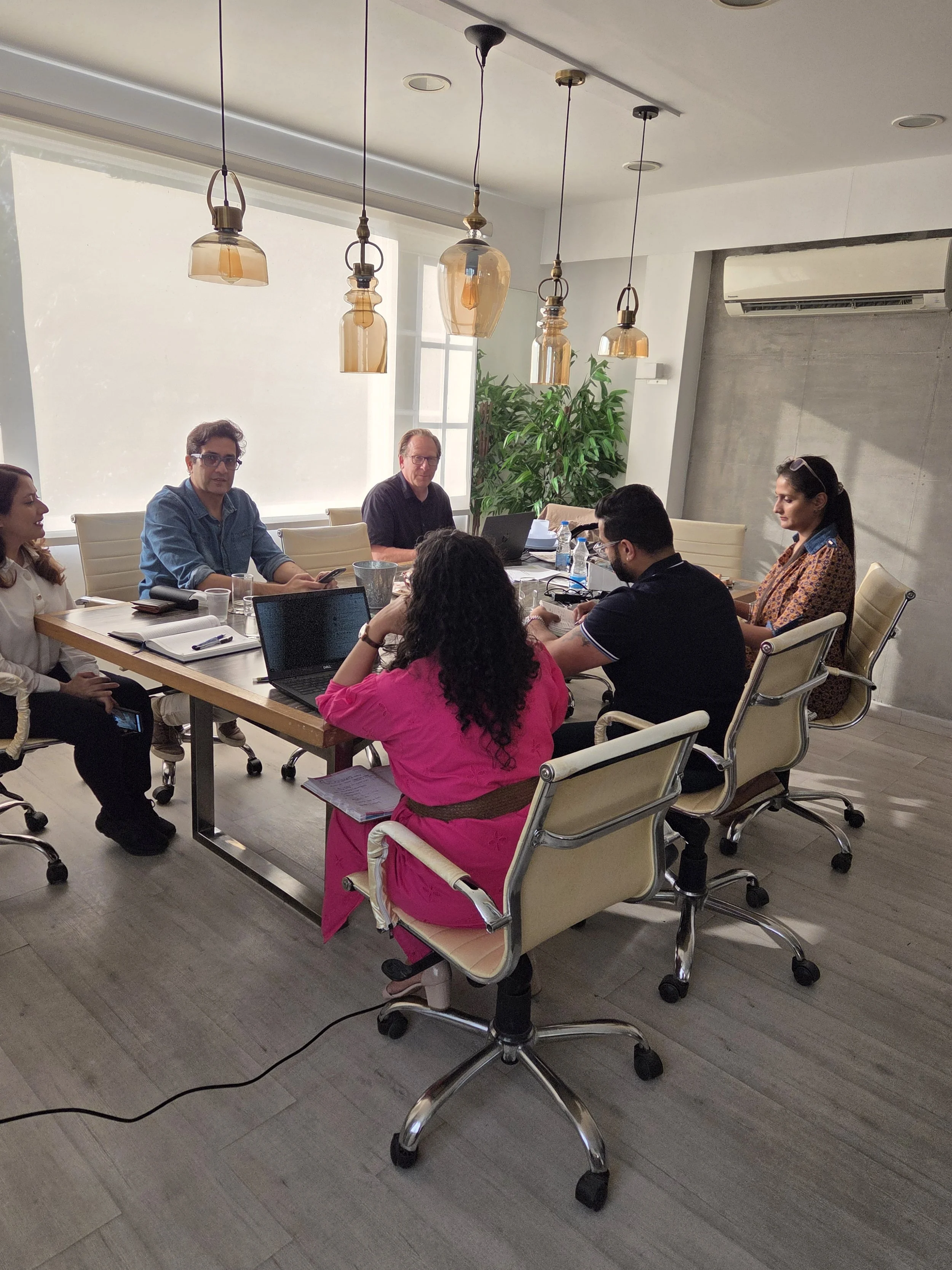 People sitting around a conference table in a meeting room, working on laptops and taking notes.