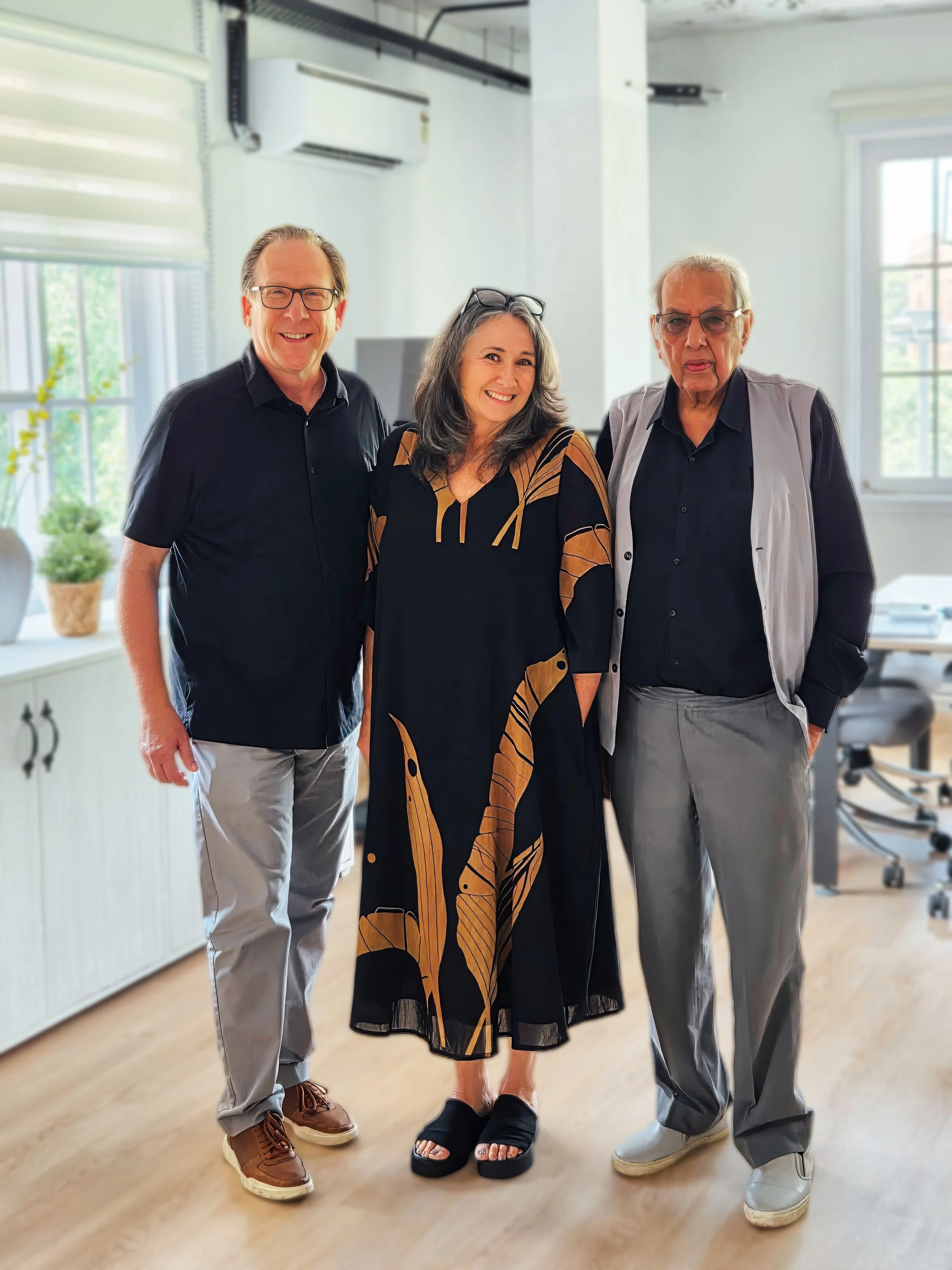 Three adults standing together in an office, smiling and posing for a photo.