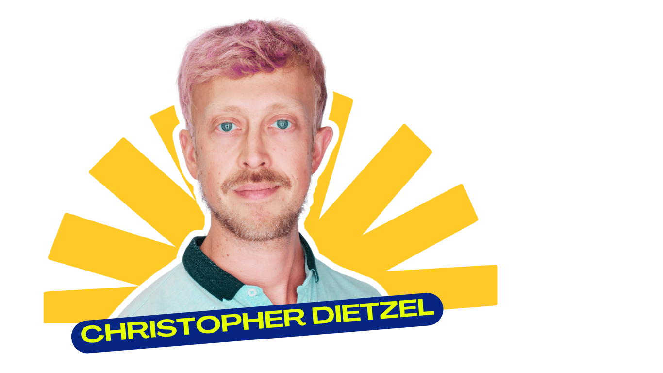A man with blonde hair, blue eyes, and a beard, wearing a light blue shirt with a dark collar, standing in front of a yellow and black background with text that reads "CHRISTOPHER DIETZEL."