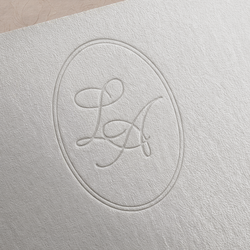 Embossed letter "L" and "A" inside an oval on a textured white paper surface.