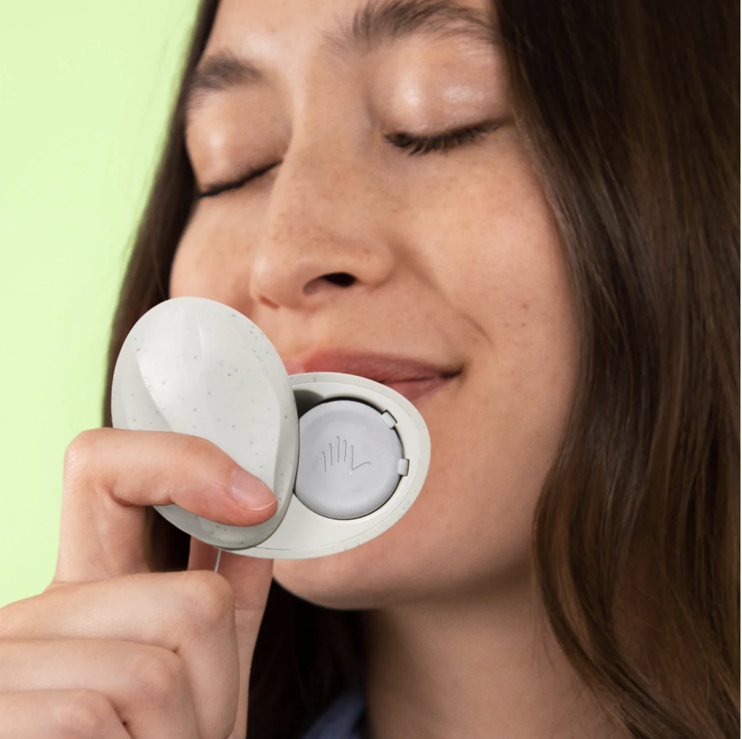 A woman with closed eyes is holding a medical device near her face, with a white circular component.