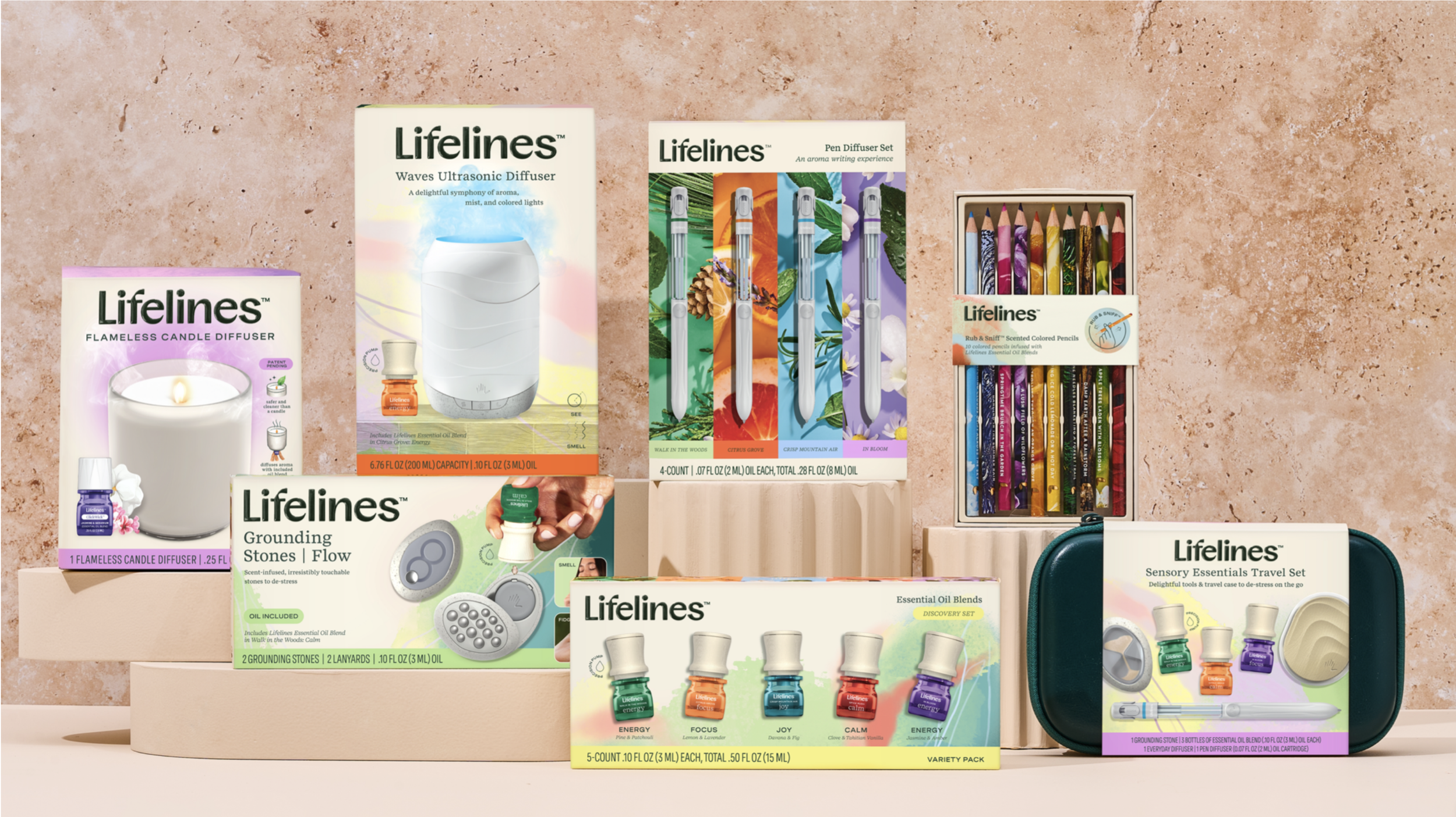 Various Lifelines aromatherapy and wellness products, including diffusers, essential oils, colored pencils, grounding stones, and travel essentials, displayed on a pink textured background.
