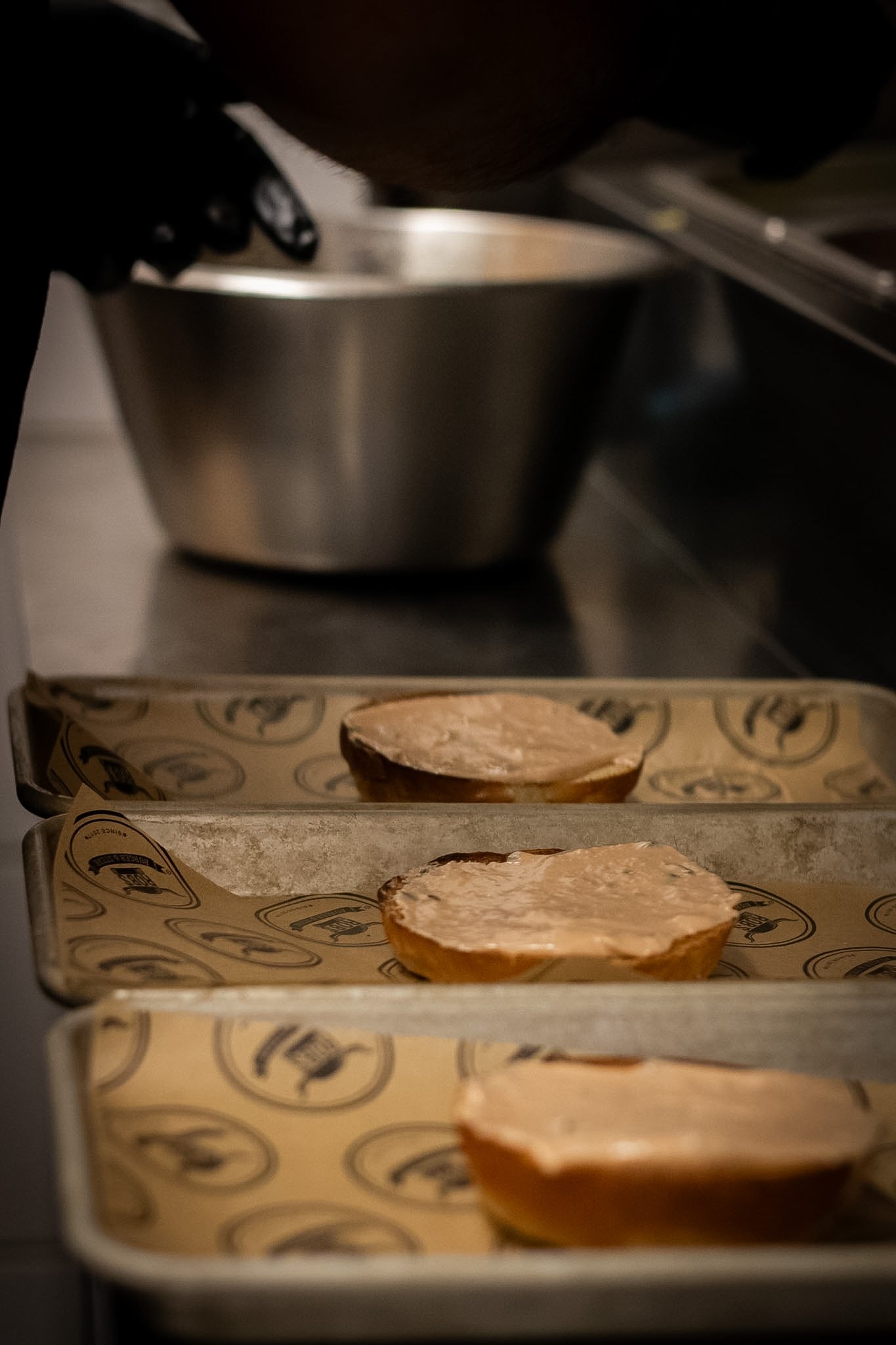Cookies cooling on parchment paper in a metal bakery tray, inside an oven.