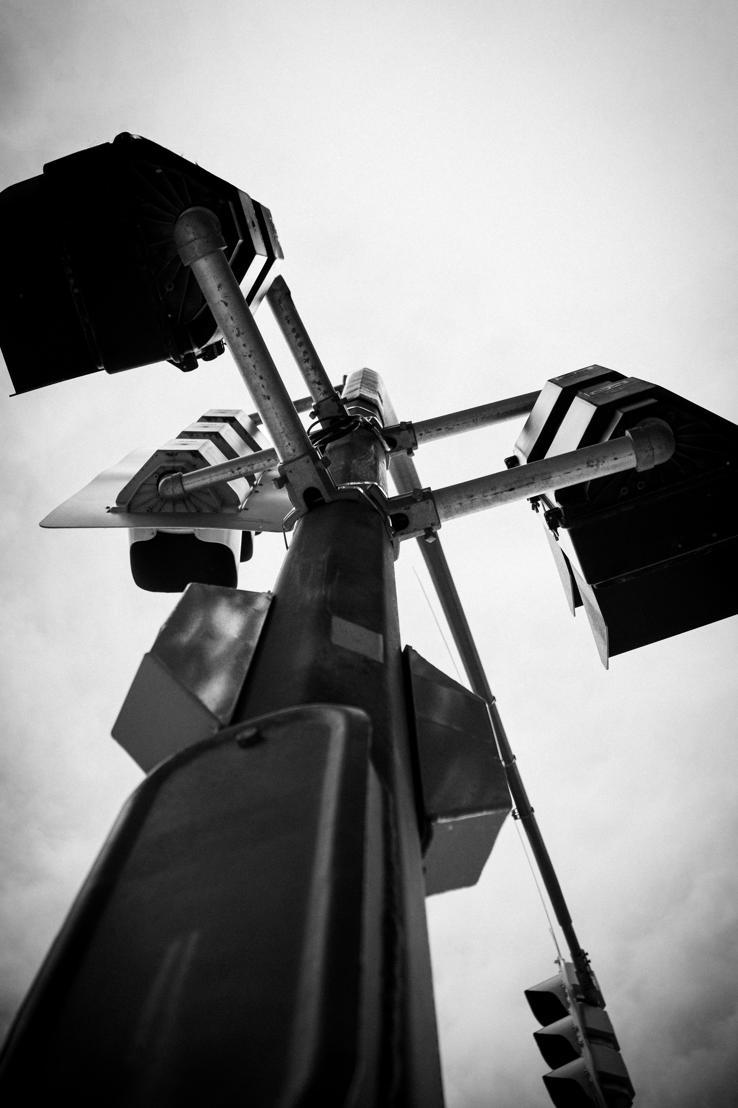 Black and white photo of a traffic light and a streetlight from below, against an overcast sky.
