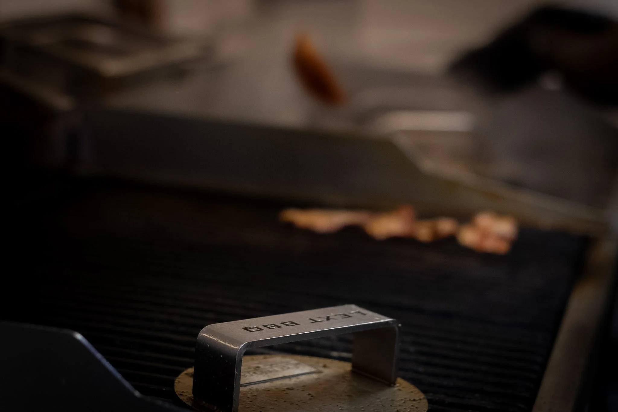 Close-up of a metallic pizza cutter with the word 'PIZZA' engraved on it, resting on a round pizza crust.