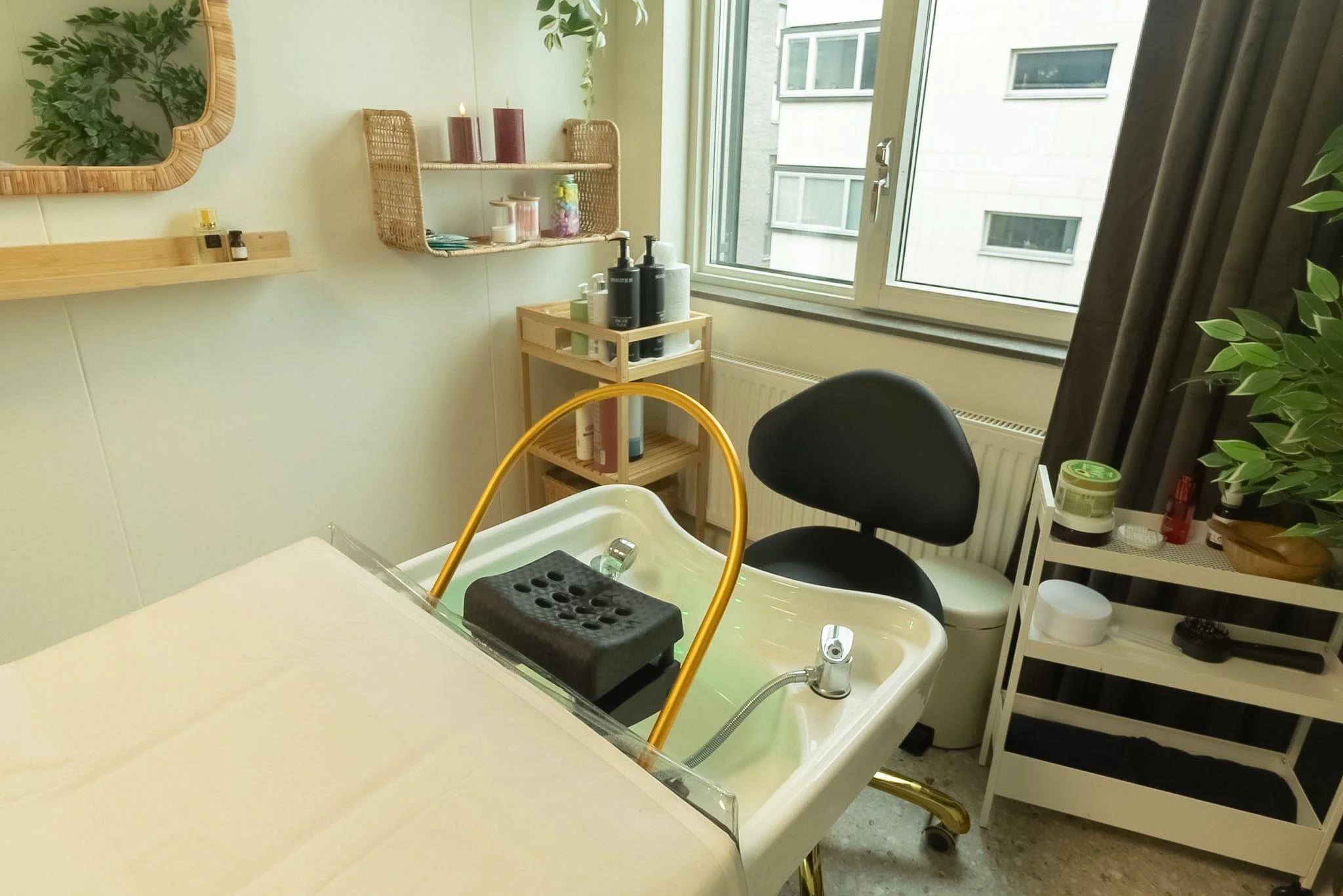 A room with a kitchen sink, surrounded by shelves and plants, near a window with city buildings outside.