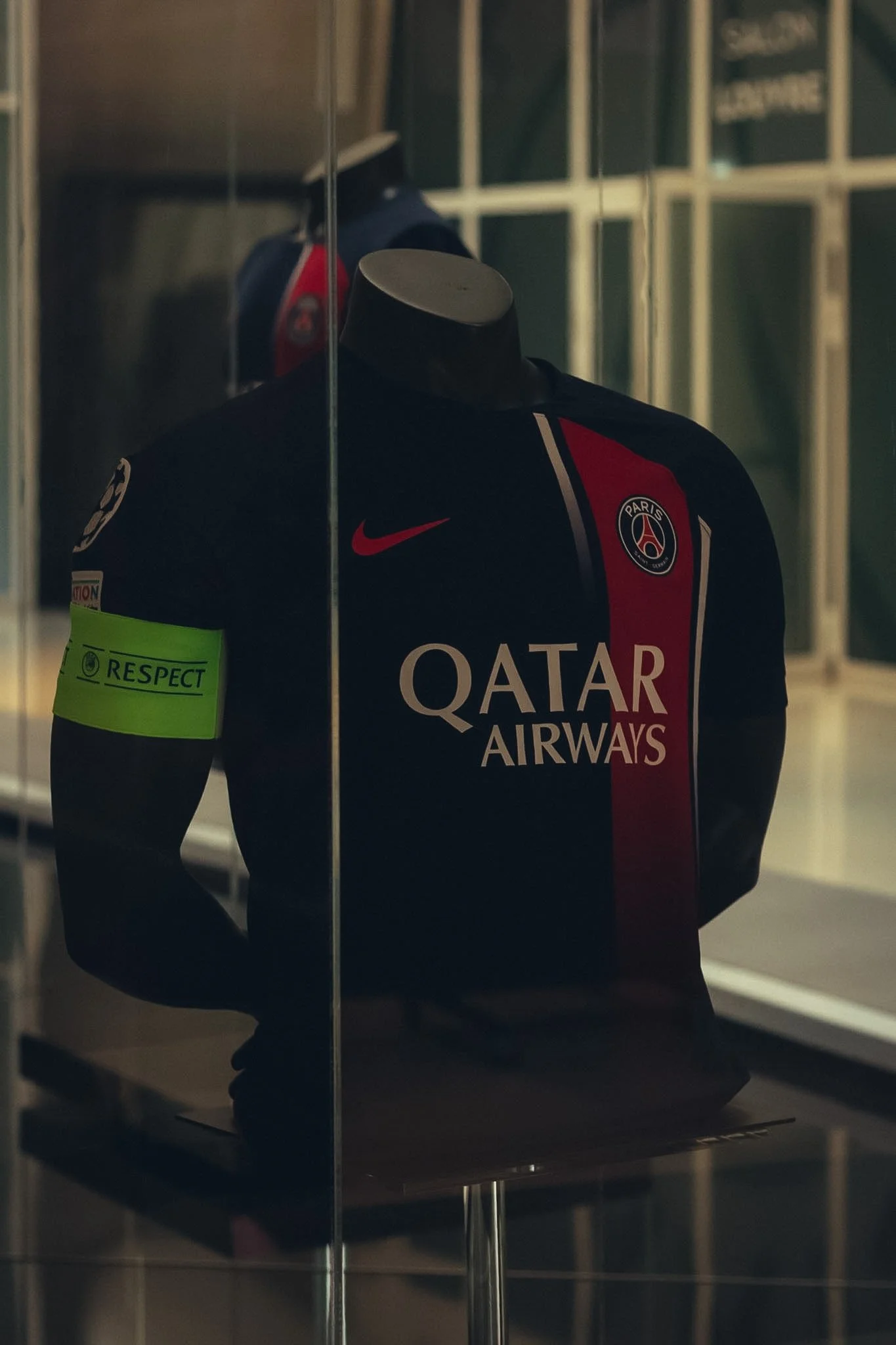 Jersey of Paris Saint-Germain football club with Qatar Airways sponsorship, displayed in a glass case at a museum or exhibit