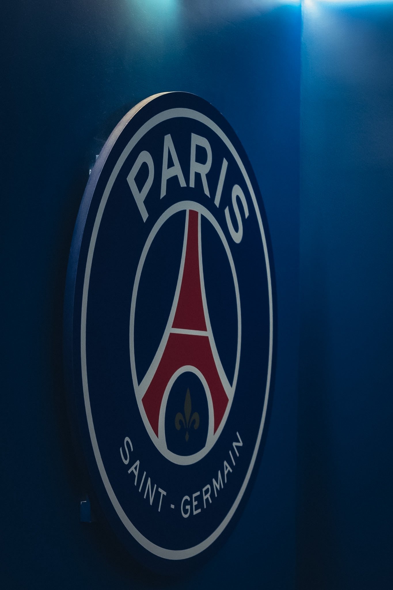 Close-up of a circular logo on a blue surface with the words "PARK" and "SAINT-GERMAIN" visible, possibly related to a sports team or organization.