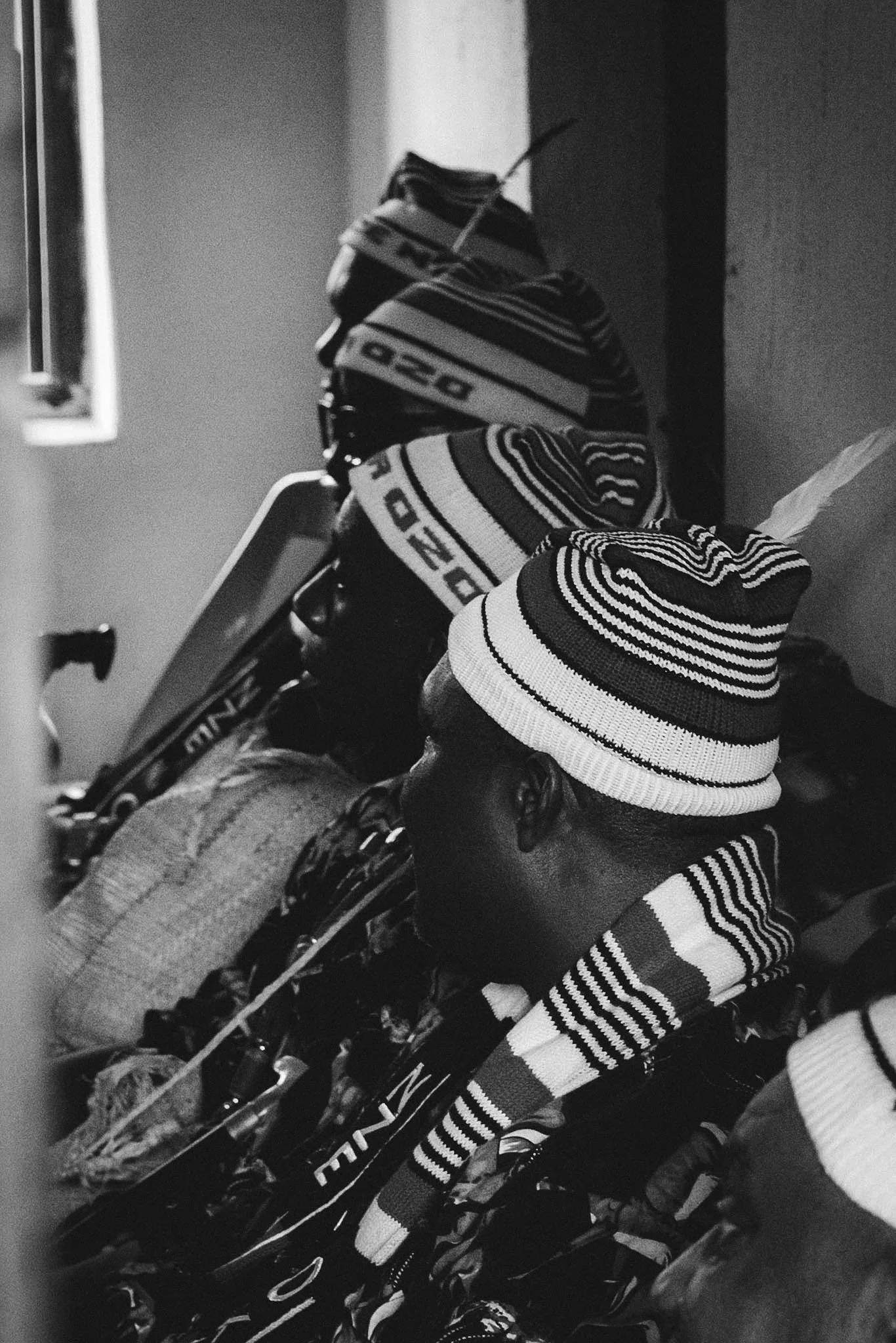 A collection of striped knit hats and gloves hanging on a rack.