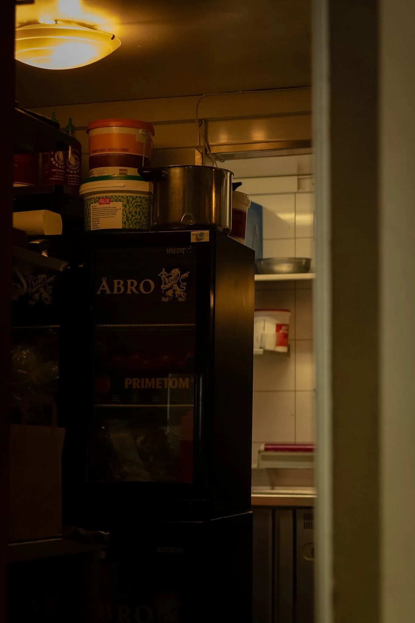 View of a kitchen pantry with shelves containing various containers and a kept door partially open, revealing a vending machine inside.