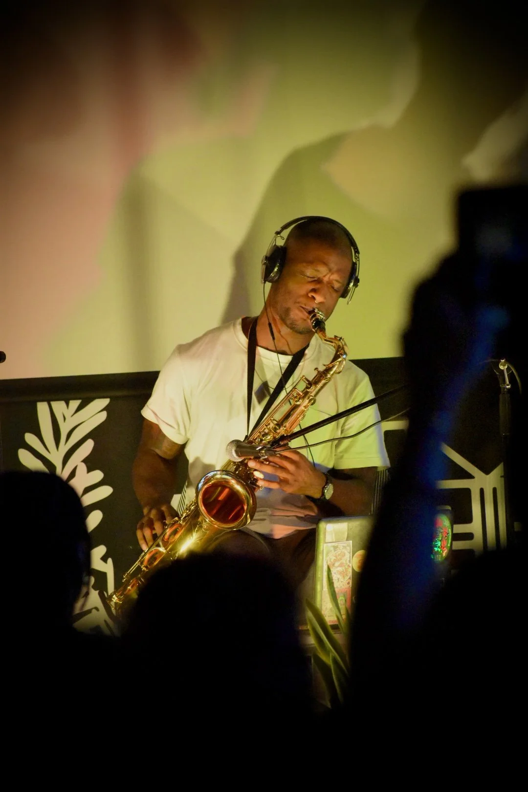 A man playing a saxophone while wearing headphones during a live performance.