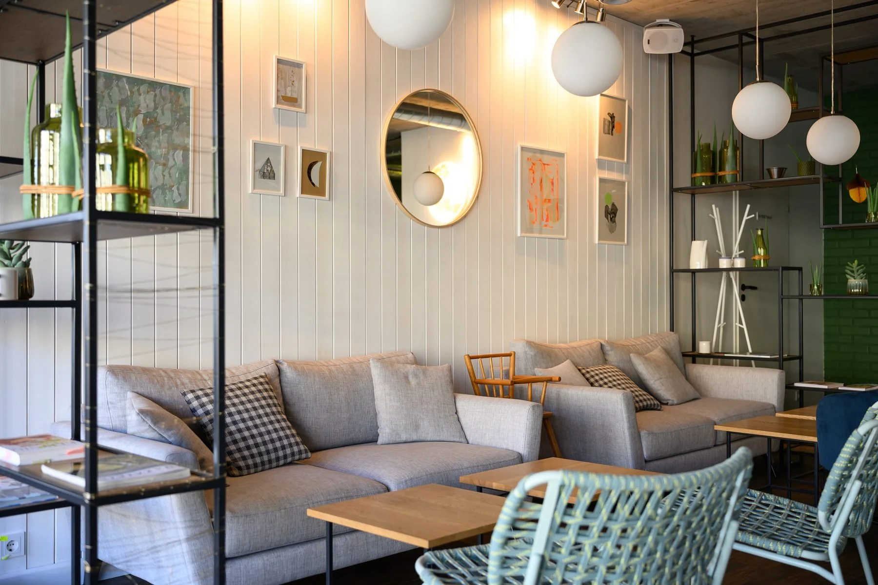 „Kažkas skanaus" kavinės poilsio erdvė su sofa, staliukais ir dekoru.