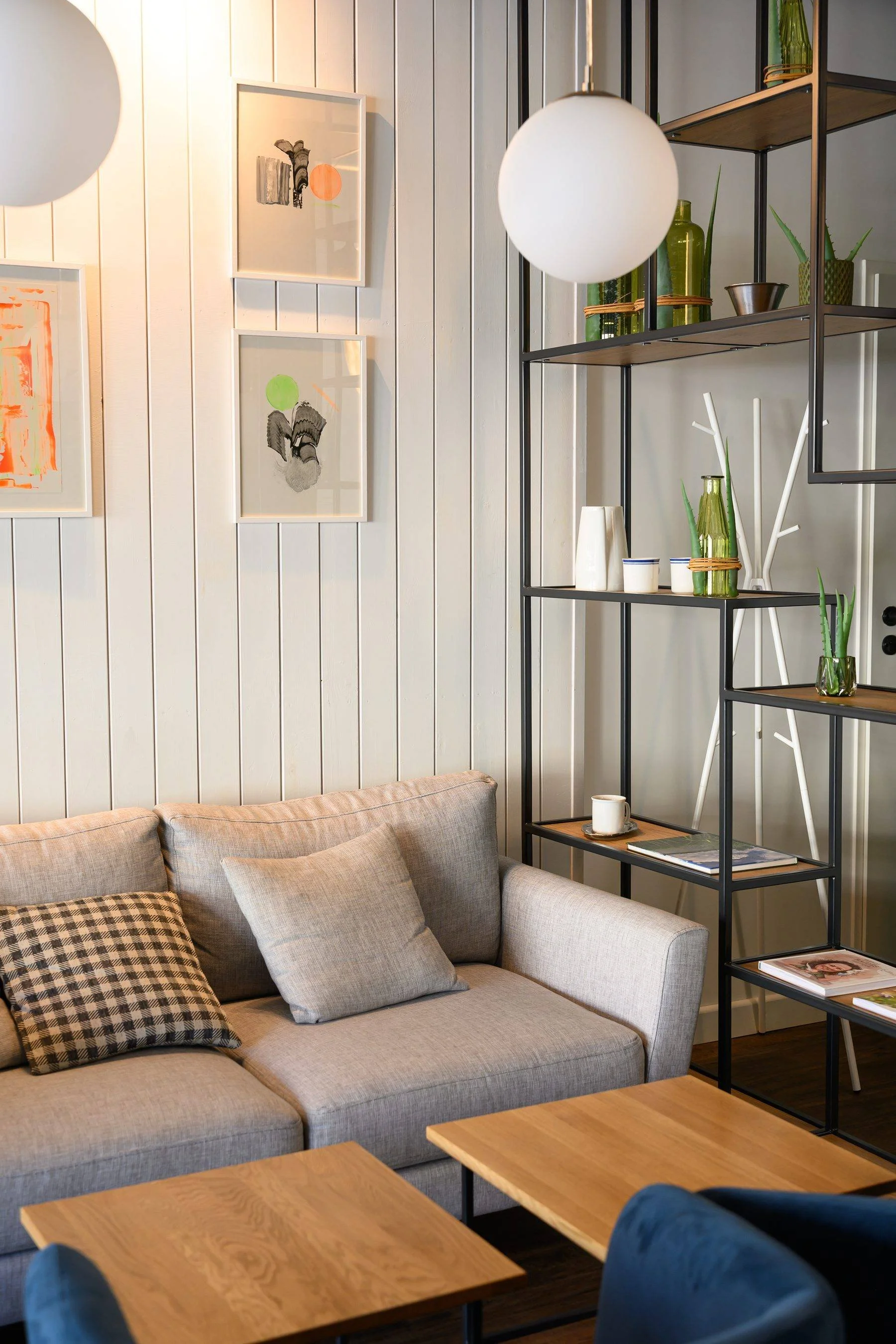 Jauki „Kažkas skanaus" kavinės erdvė su sofa, staliuku ir dekoratyvine lentyna.