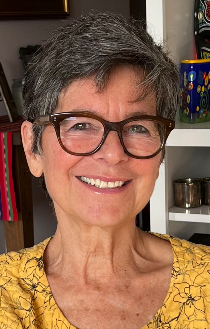 A smiling woman with short gray hair and glasses