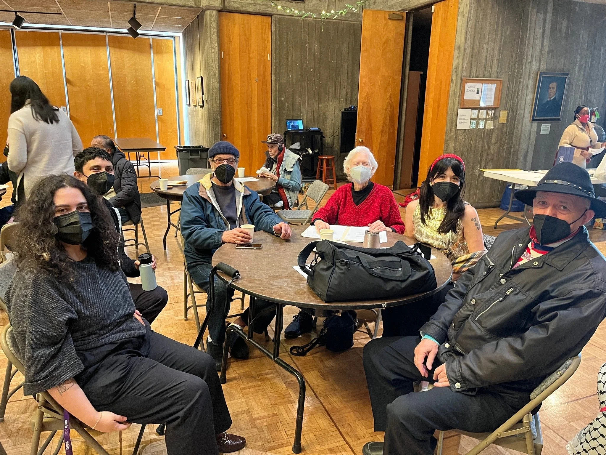 A group of masked people sitting around a table