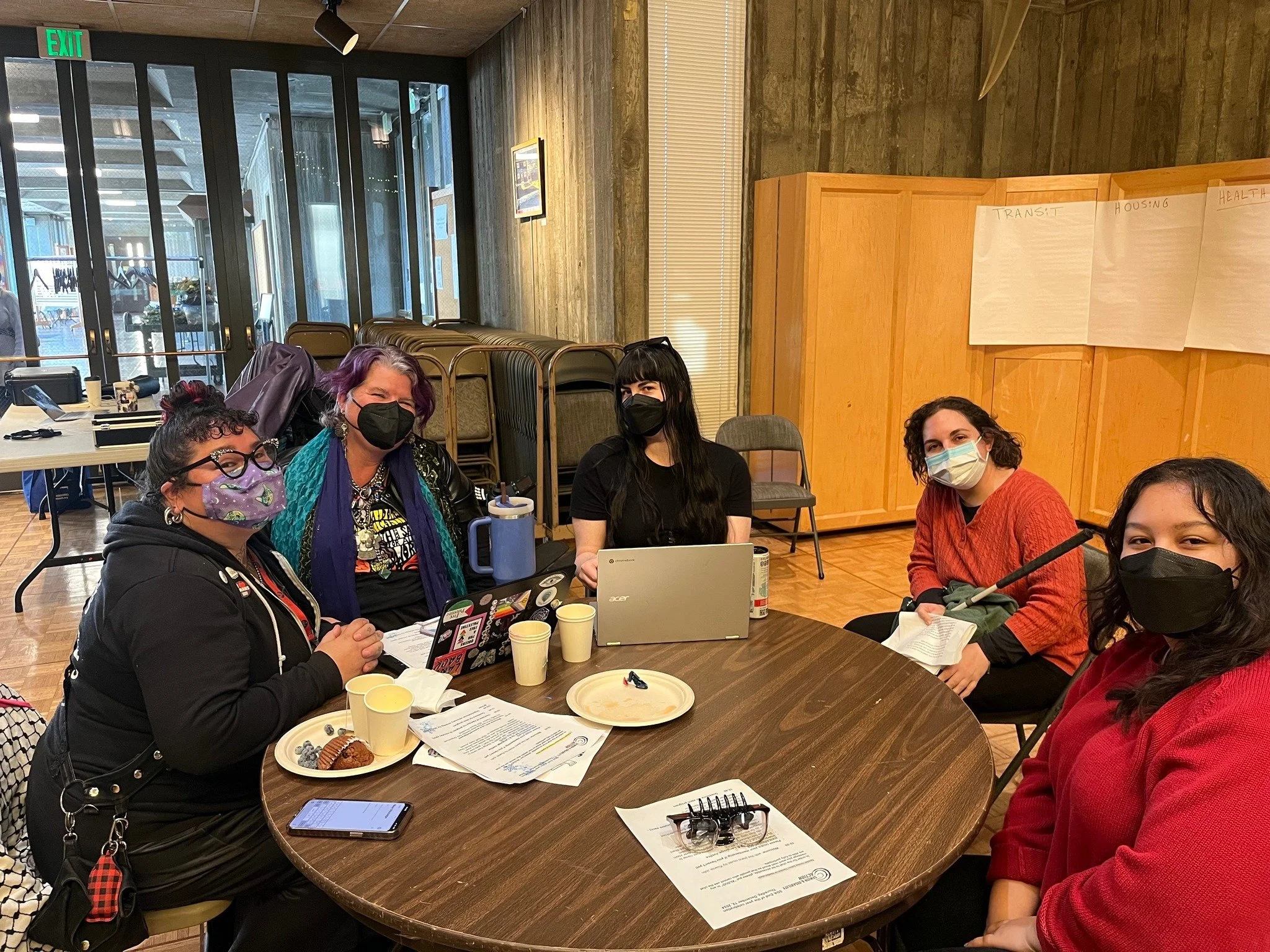 A group of masked people sitting around a table
