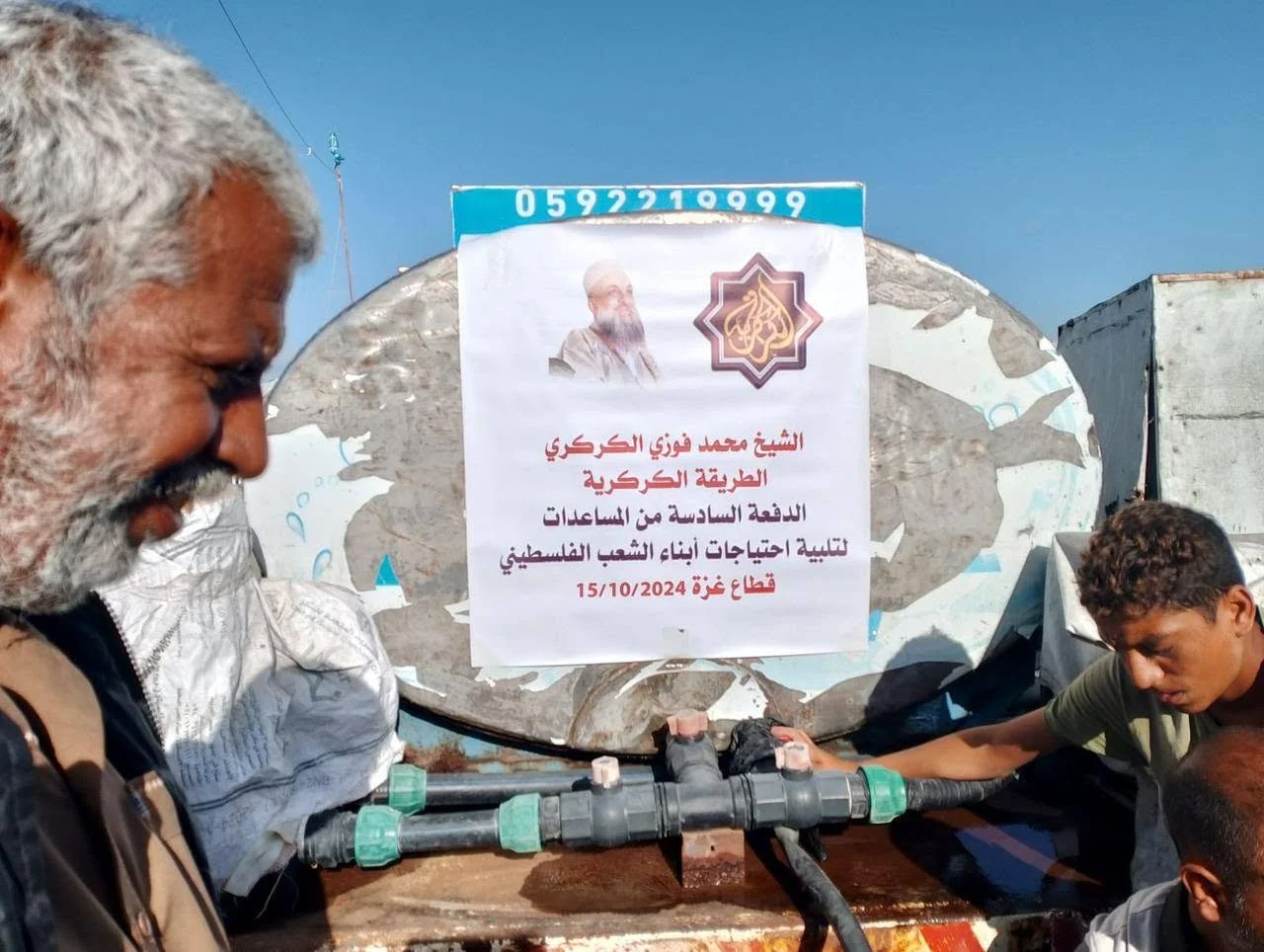 People working on water pipes outdoors with a sign in Arabic and an Al Jazeera logo.
