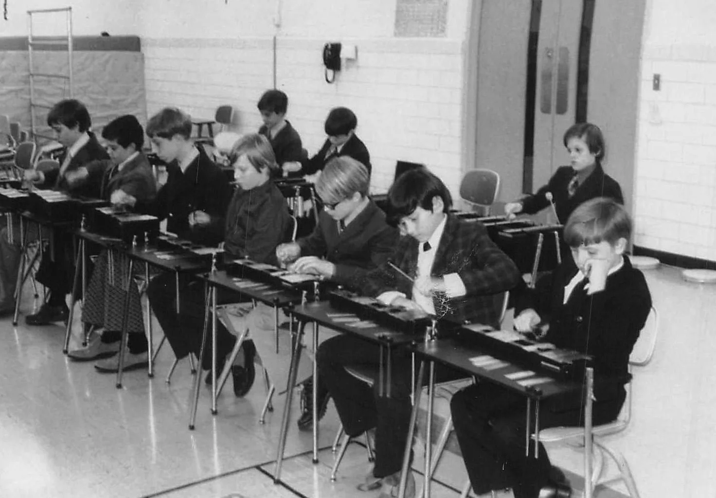 Black and white historical photo of young children playing xylophones during a music class in a school setting.