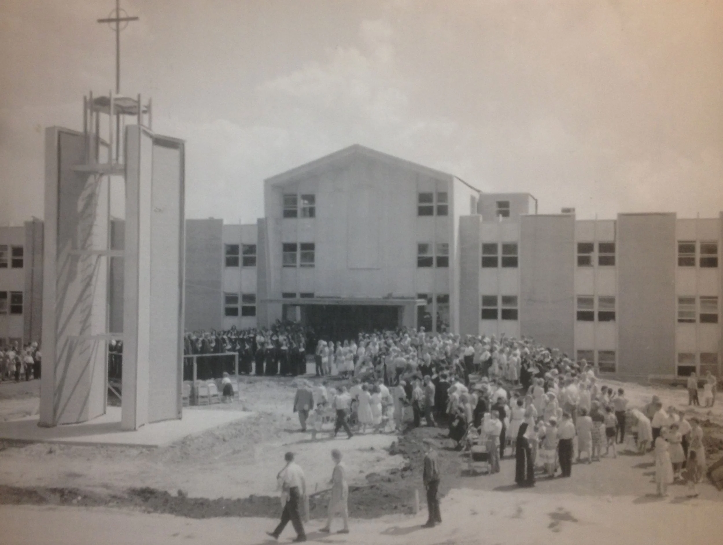 Black and white photo of a large group of students standing in formation outside a school building.