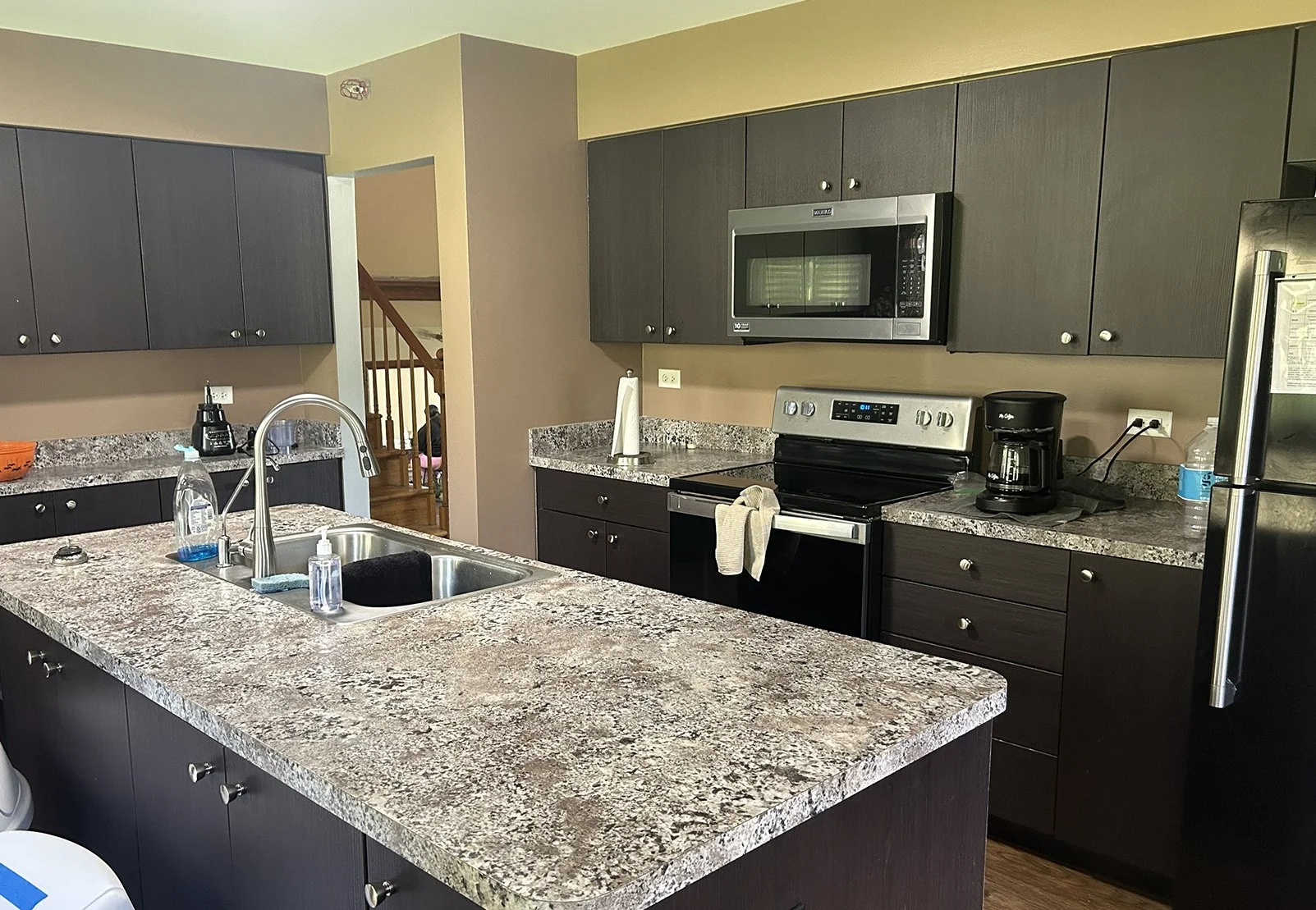 Kitchen with granite countertops, dark cabinets, stainless steel appliances, and a double sink.
