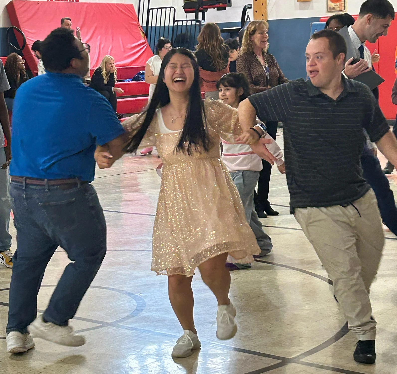 Two Clare Woods participants dance merrily with their teacher, wearing a sparkly dress.