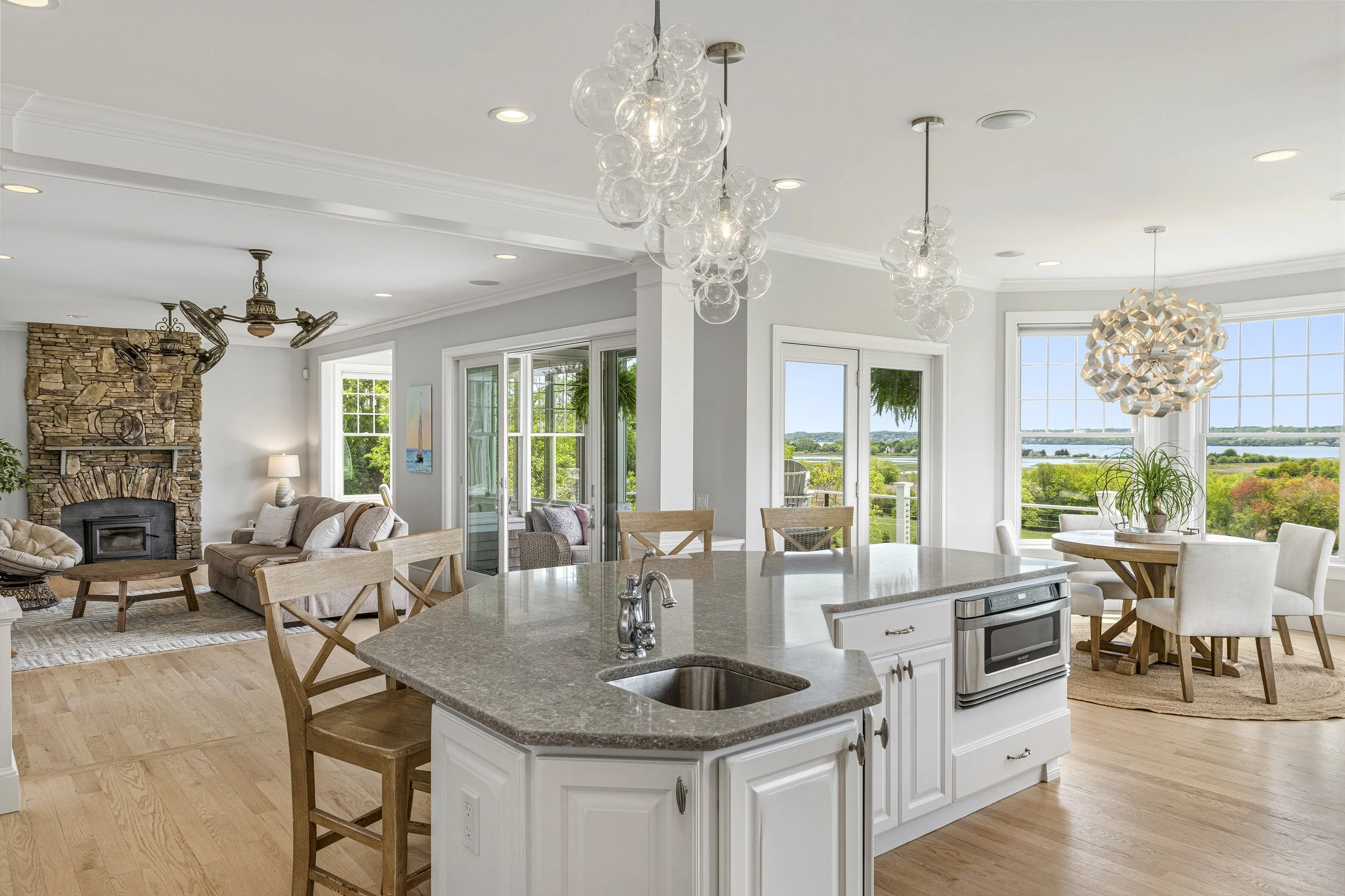 Bright open-concept living and dining area with large windows, modern chandeliers, and a kitchen island.