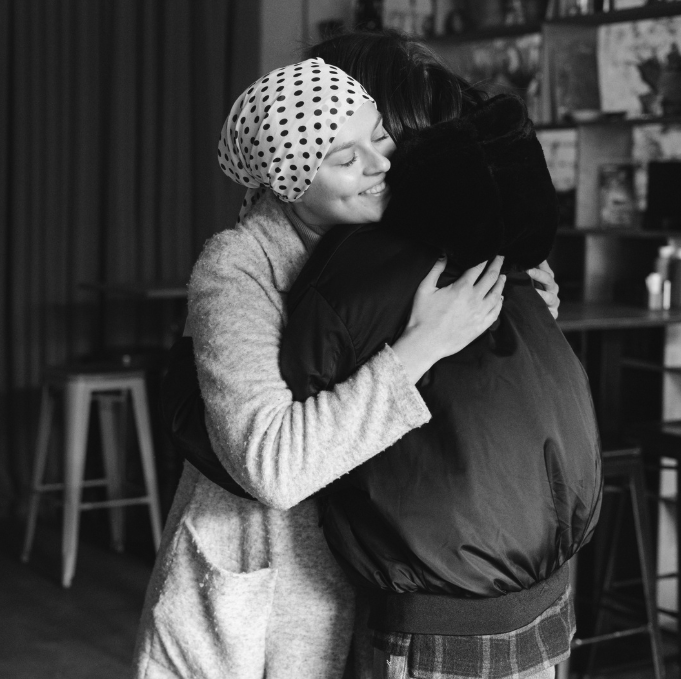 Someone with terminal cancer in hospice giving someone else a hug who has anticipatory grief