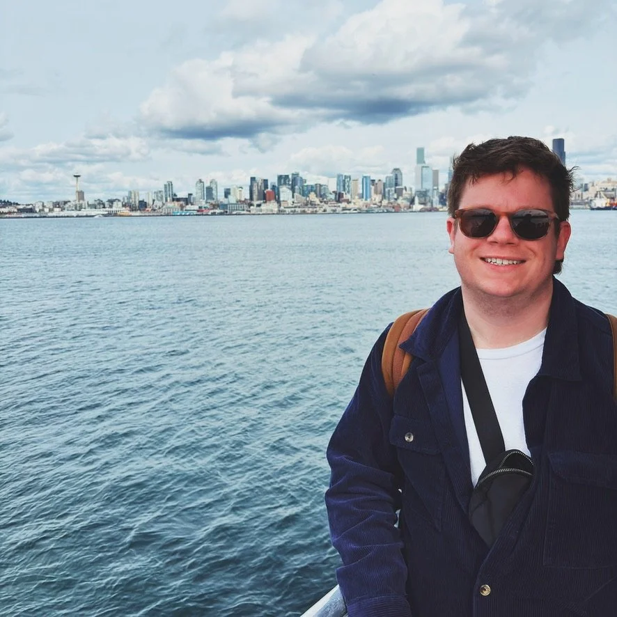 Jordan Crosby grief therapist in west seattle at the west seattle center for grief, loss, and transition standing in front of the seattle skyline