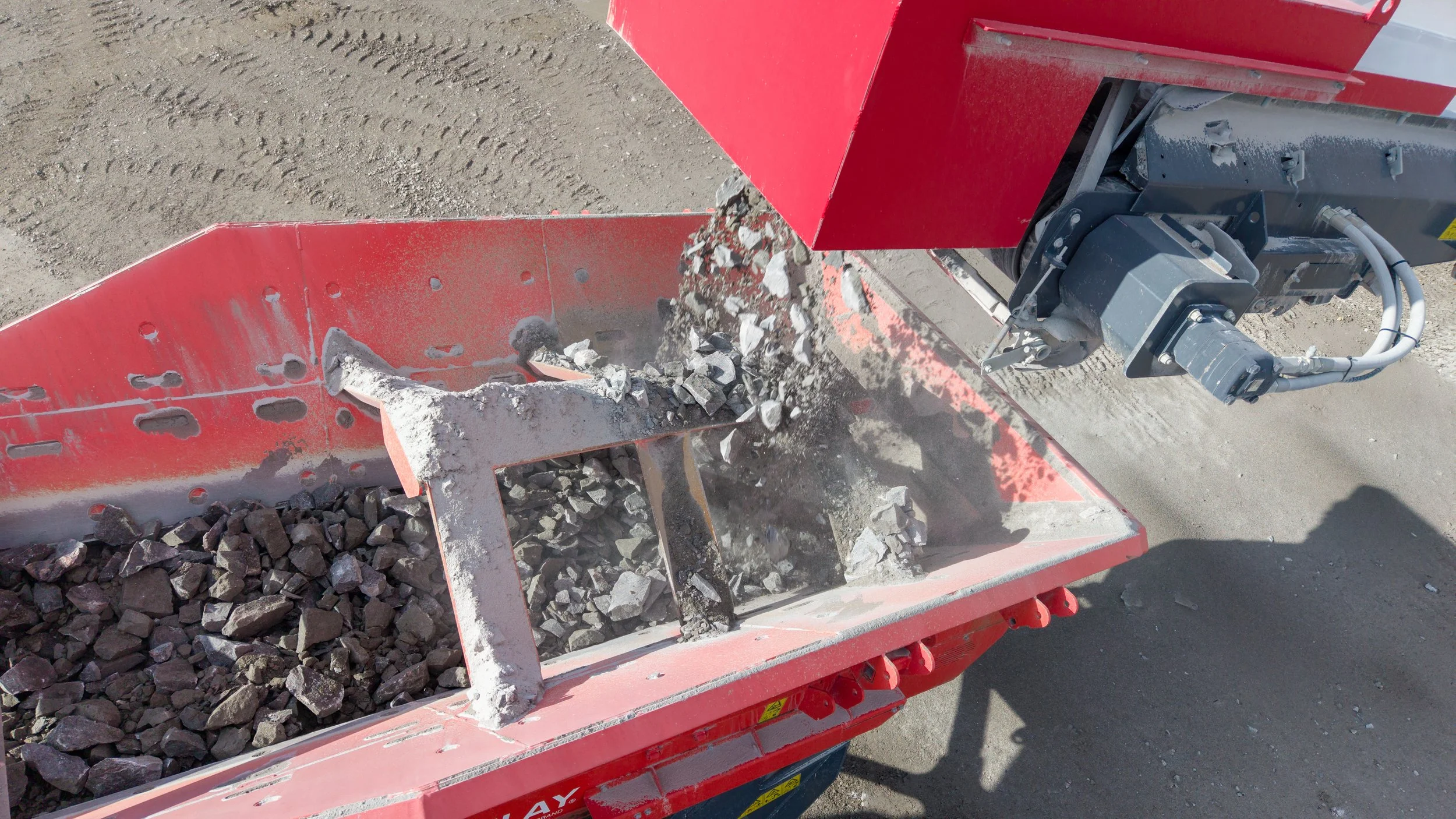 A construction machine blending rocks and debris into a conveyor system.