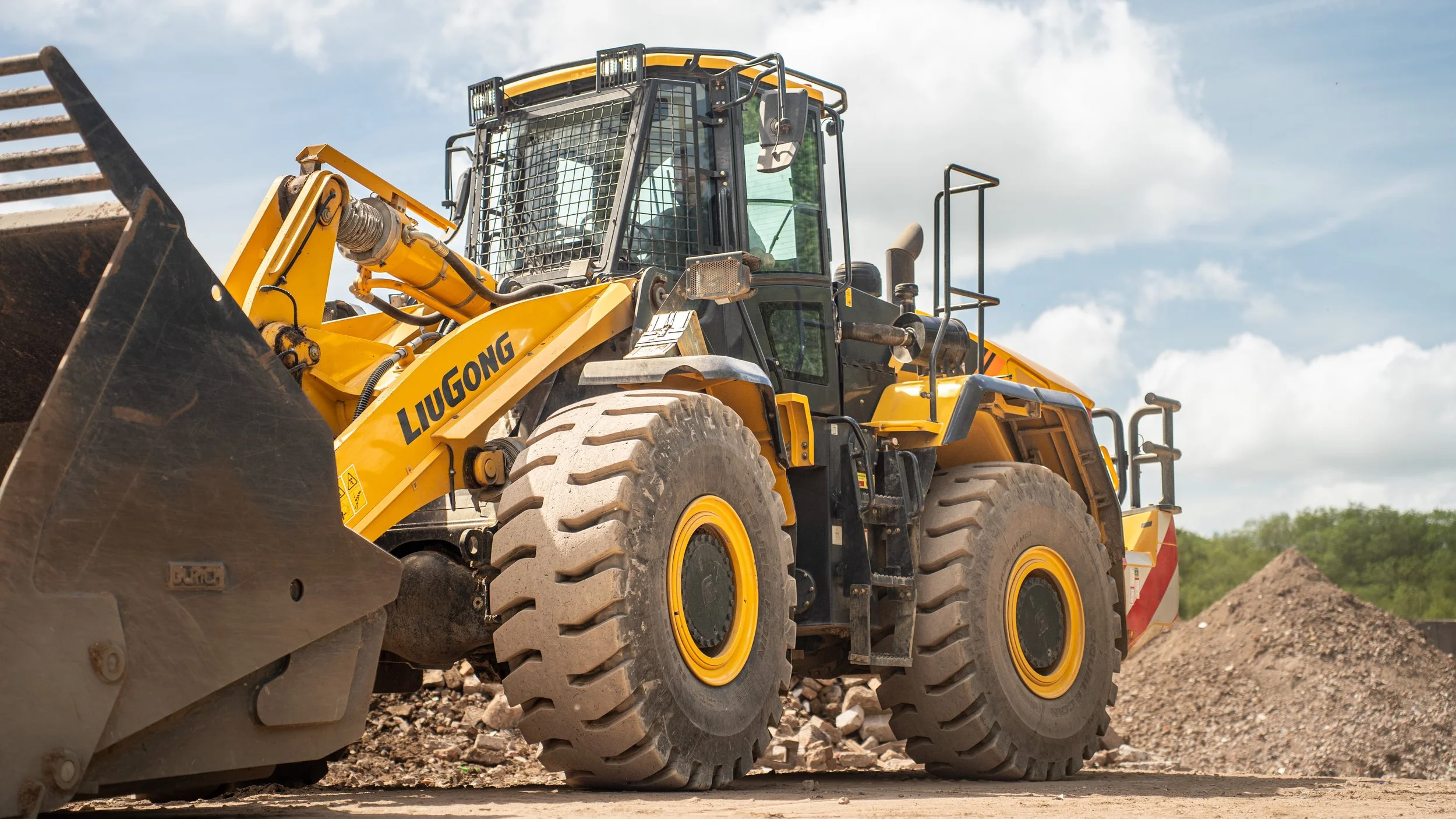 Yellow LiuGong front loader construction vehicle on dirt site under a cloudy sky.