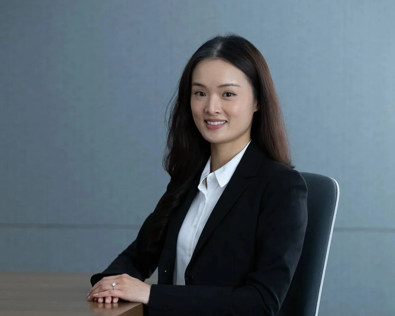 A woman in a black blazer and white shirt sitting at a desk in an office.