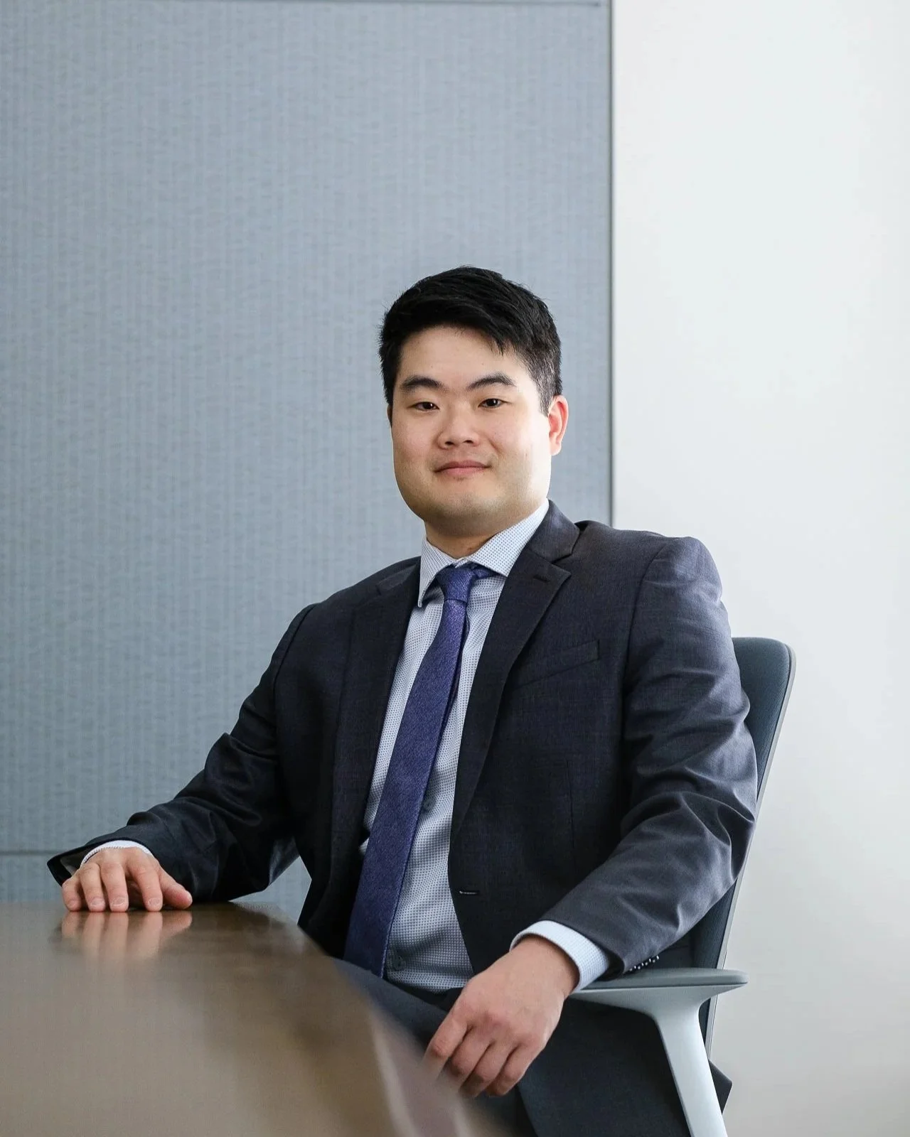 A young man in a suit and tie sitting at a conference table in an office.