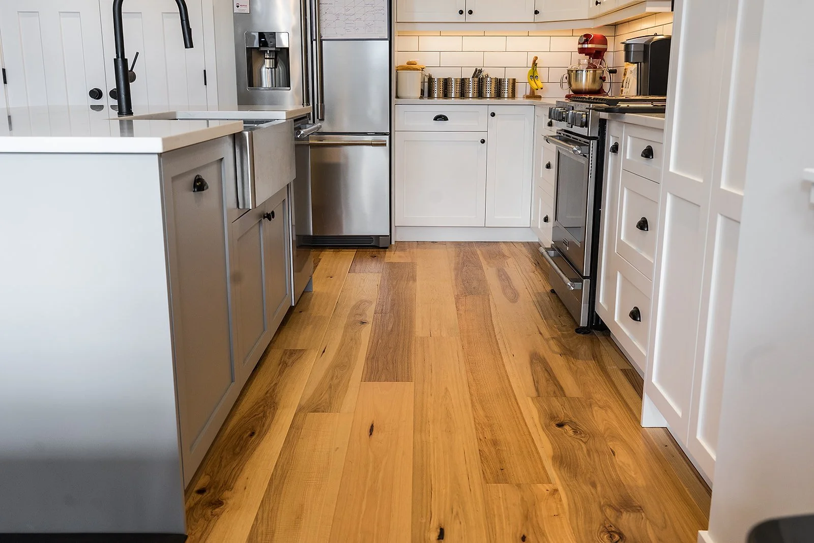 Kitchen with white cabinets, stainless steel appliances, and wooden flooring.