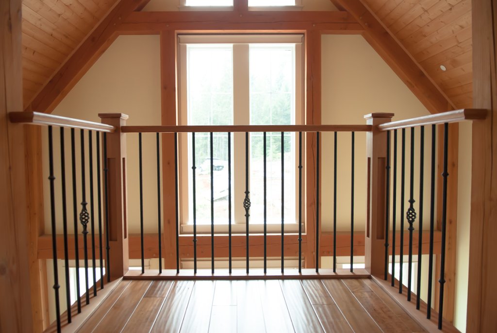 Wooden interior of a room with a window and railing, possibly a loft or balcony area.