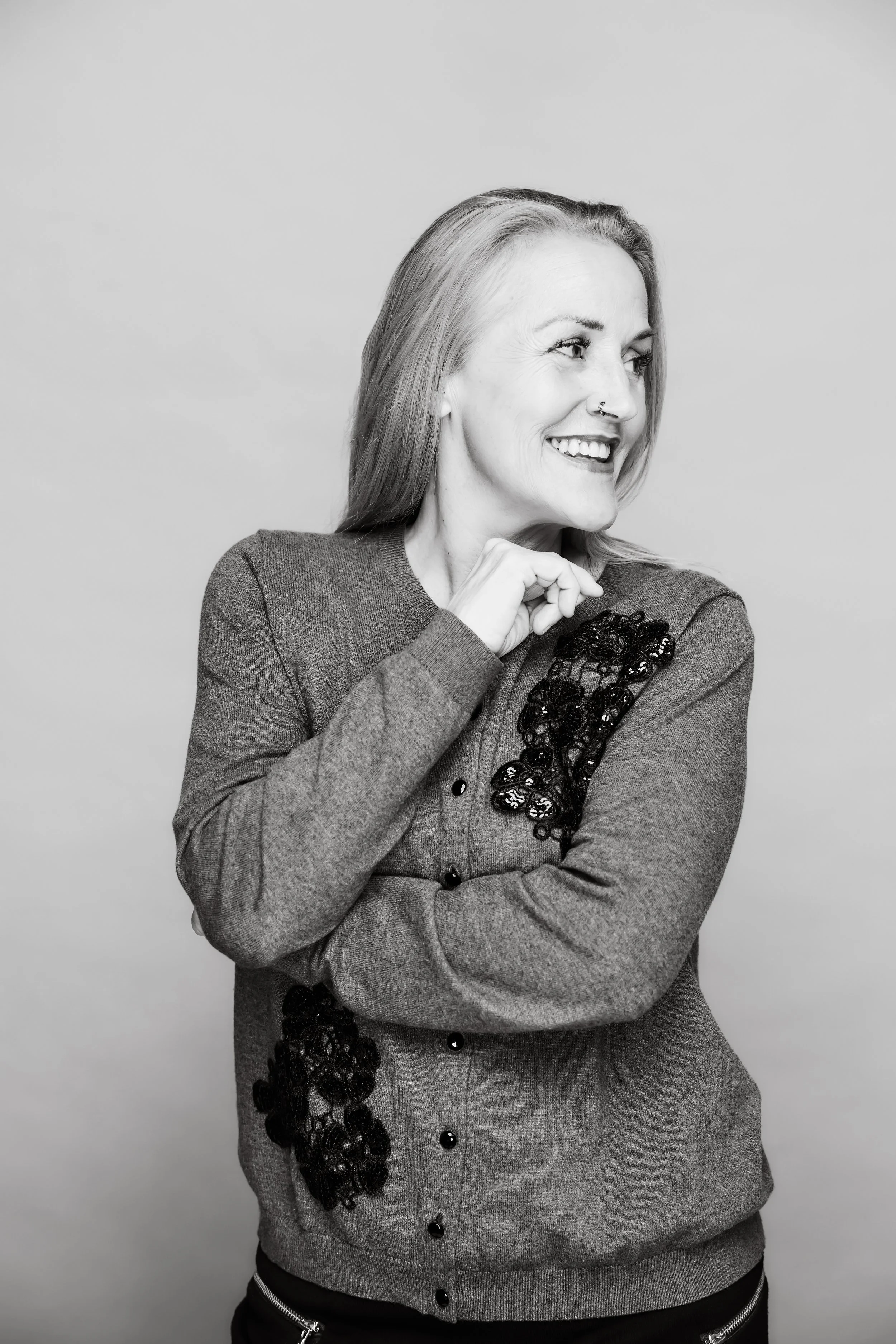 Black-and-white portrait of smiling woman in textured gray sweater against a light background