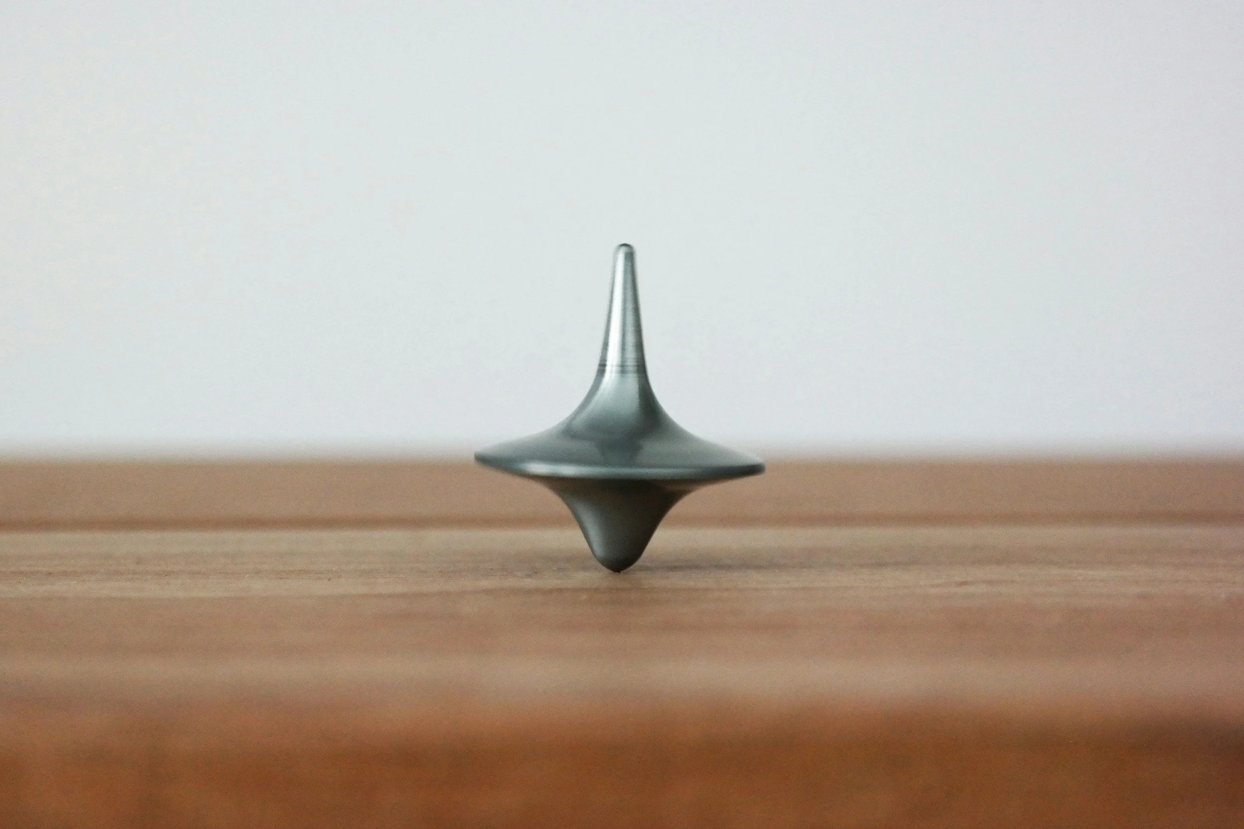 A close-up view of a spinning top on a wooden surface with a plain white background.