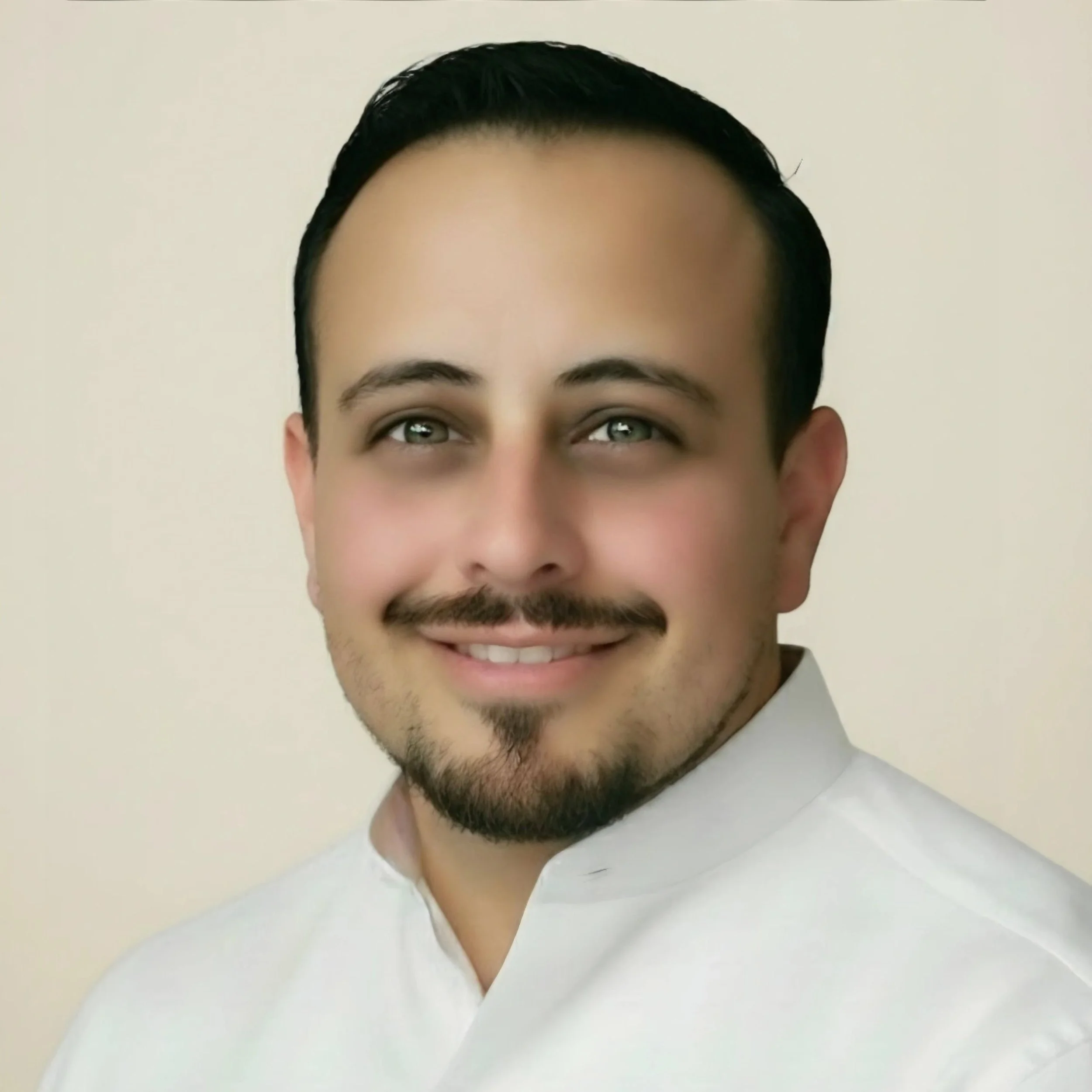 A handsome man with short dark hair, hazel eyes, and clean trimmed facial hair, gentle rising cheeks with a warm welcoming smile  wearing a white mandarin collar shirt against an open white sands background.
