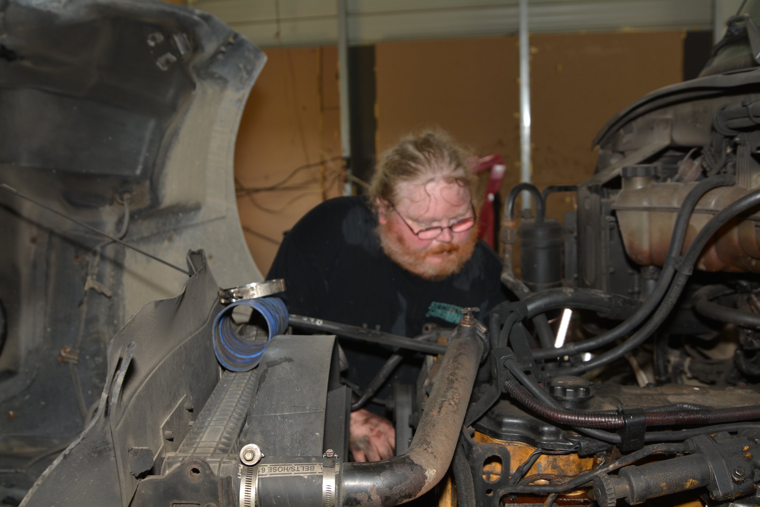 Cloyd Zimmerman working to repair a Diesel Engine inside a garage