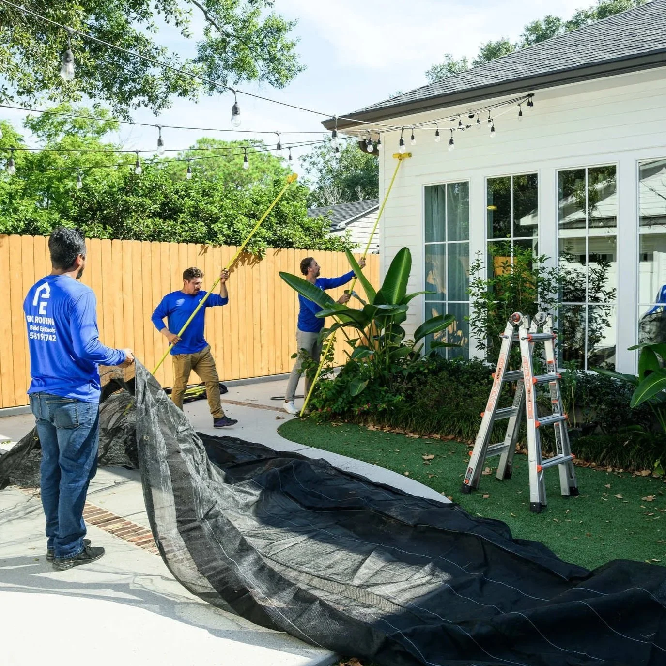 Roofing crew setting up equipment and protective materials outside Louisiana home before completing residential roof replacement and exterior roofing work.