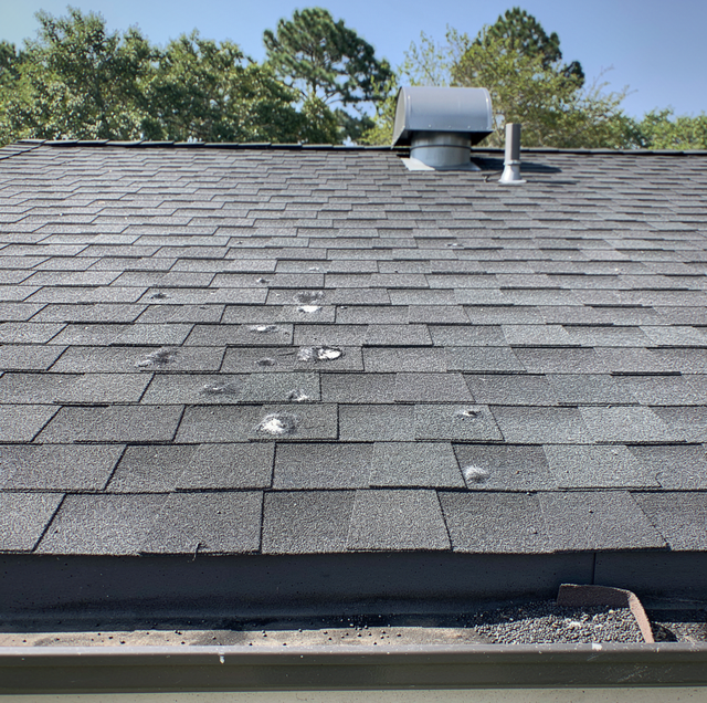 hail dented asphalt shingles on residential roof