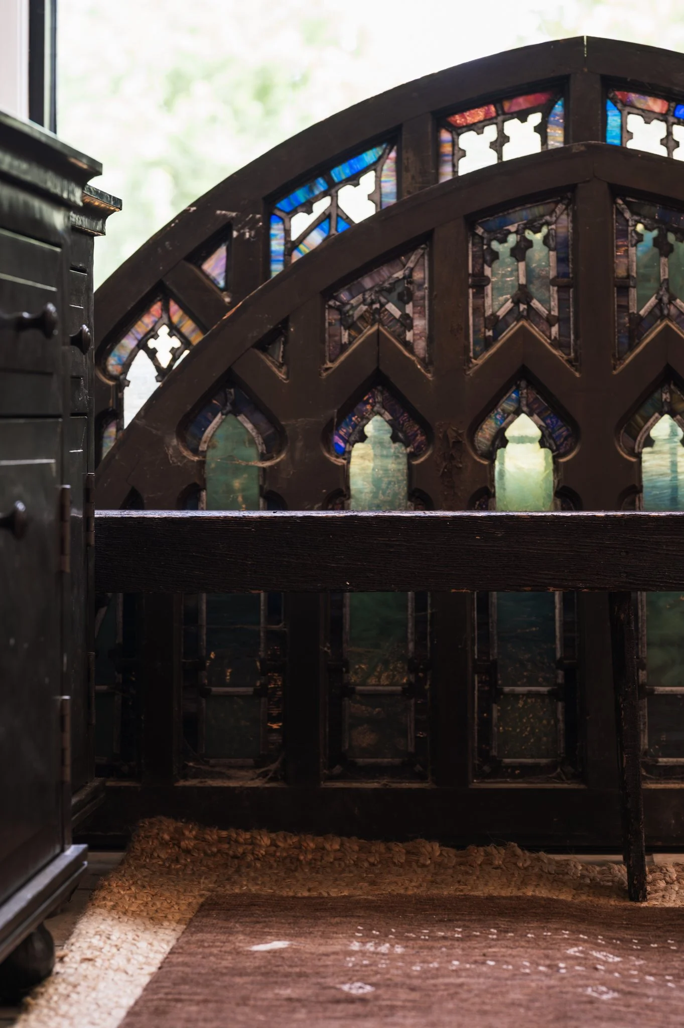 Close-up view of a wooden church pew with colorful stained glass windows behind it.
