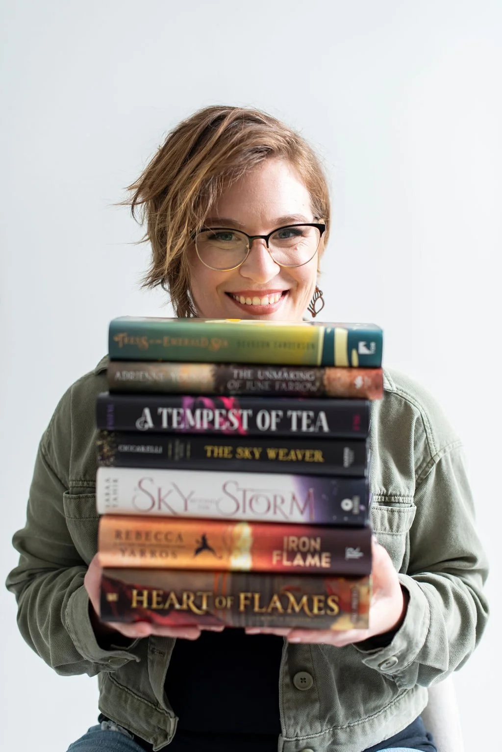 Business educator Chelsey Hart with a stack of books, sharing practical insights on entrepreneurship, marketing, business planning, and sustainable growth.