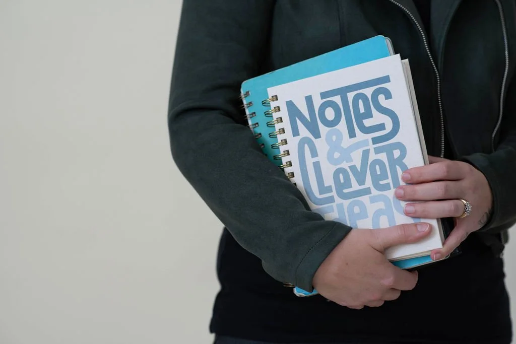 Business planning guidebook and notebook representing practical business education, marketing strategy, and entrepreneurship coaching for small business owners.