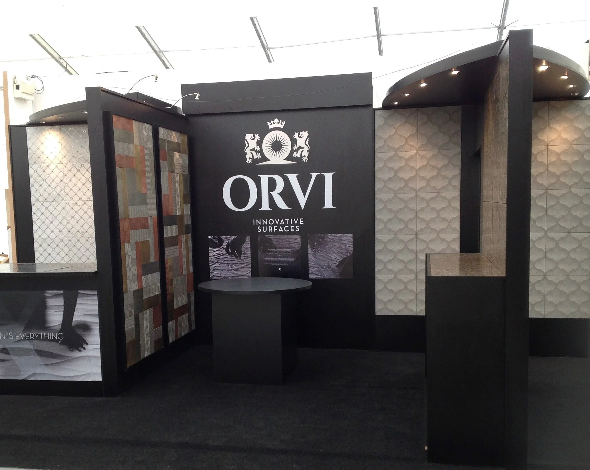 Exhibition booth for Orvi company showcasing innovative surfaces with decorative wall panels and a sleek design.