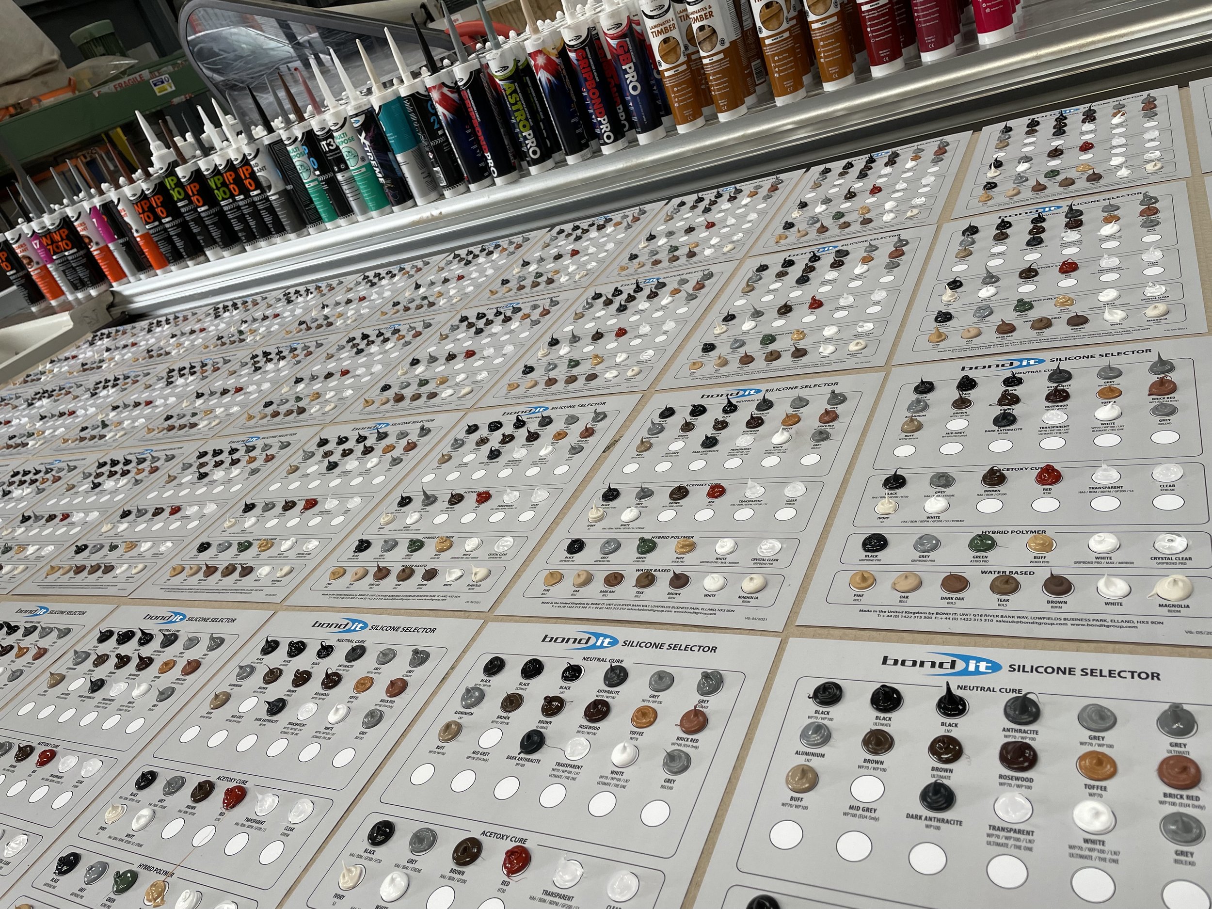 Display of silicone sealant color samples and tubes on a table in a hardware store.