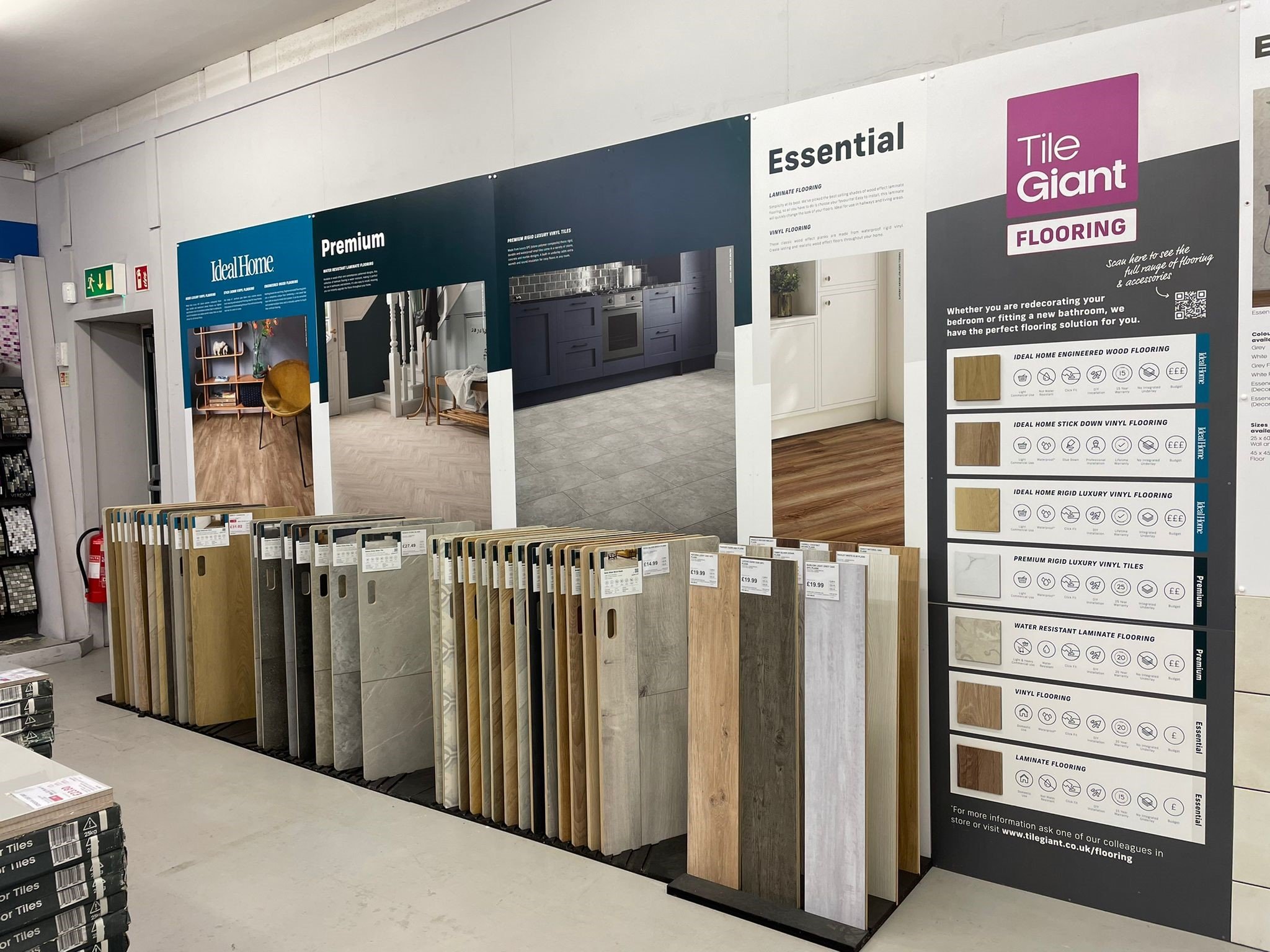 Display of various flooring samples and informational panels in a store, including wood and vinyl options from brands like Ideal Home and Tile Giant.