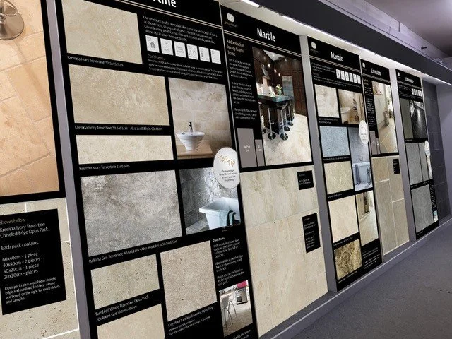 Display of various stone tiles including limestone, marble, and travertine in a showroom.